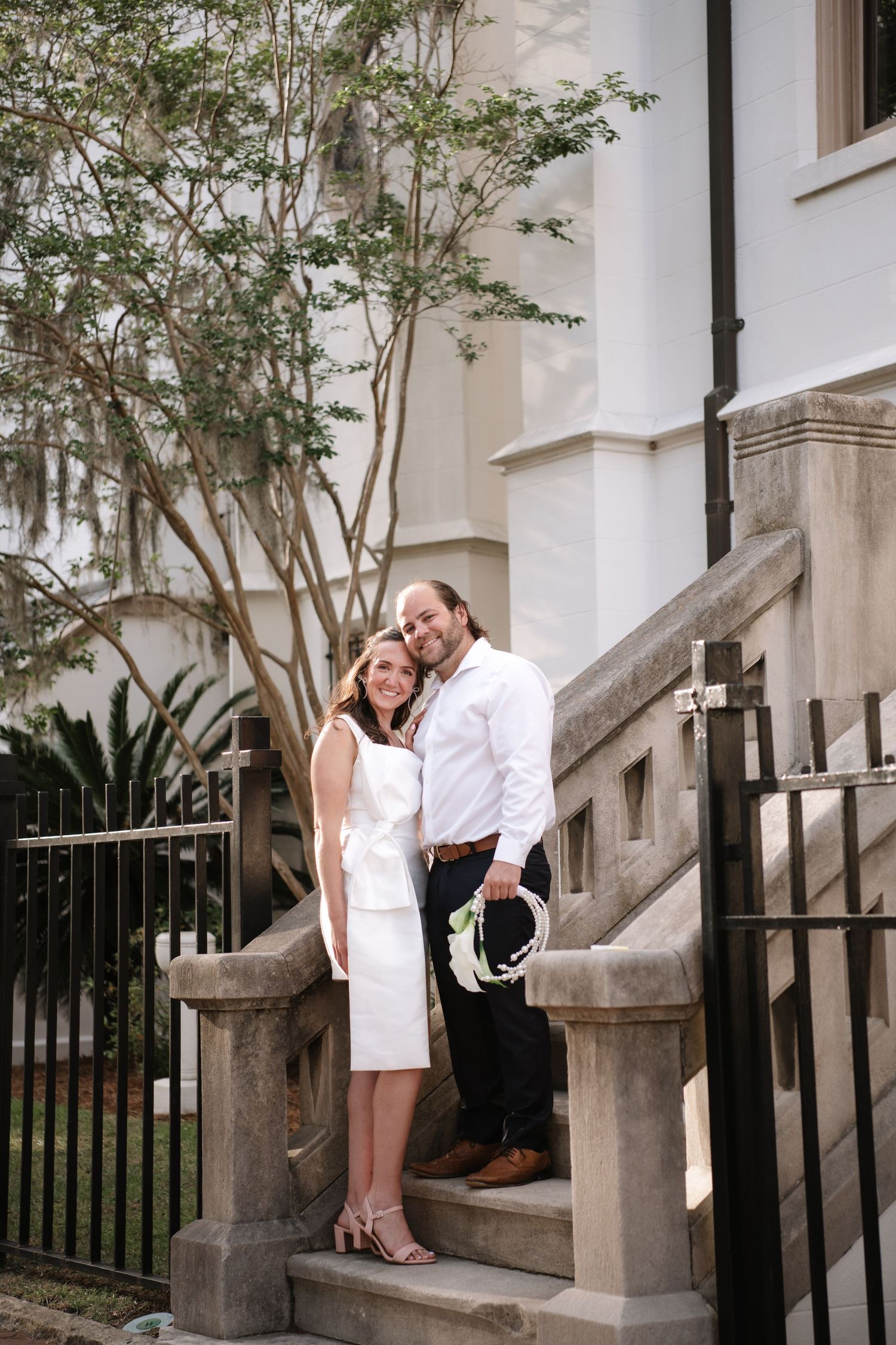 A couple shares intimate moments on white stone steps outside a classic building in a romantic photo series.