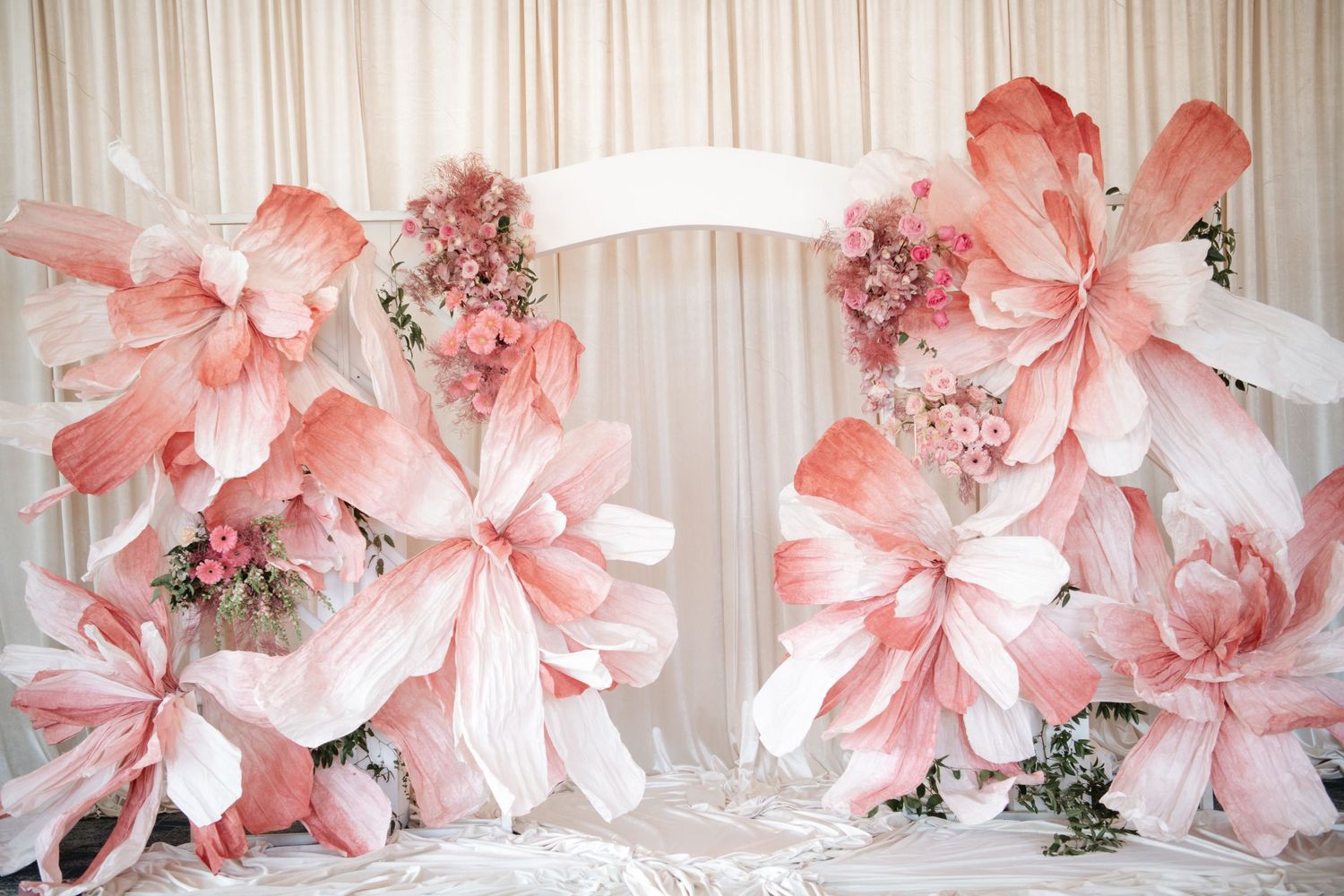 Large pink paper flower decorations adorning a white draped wall.