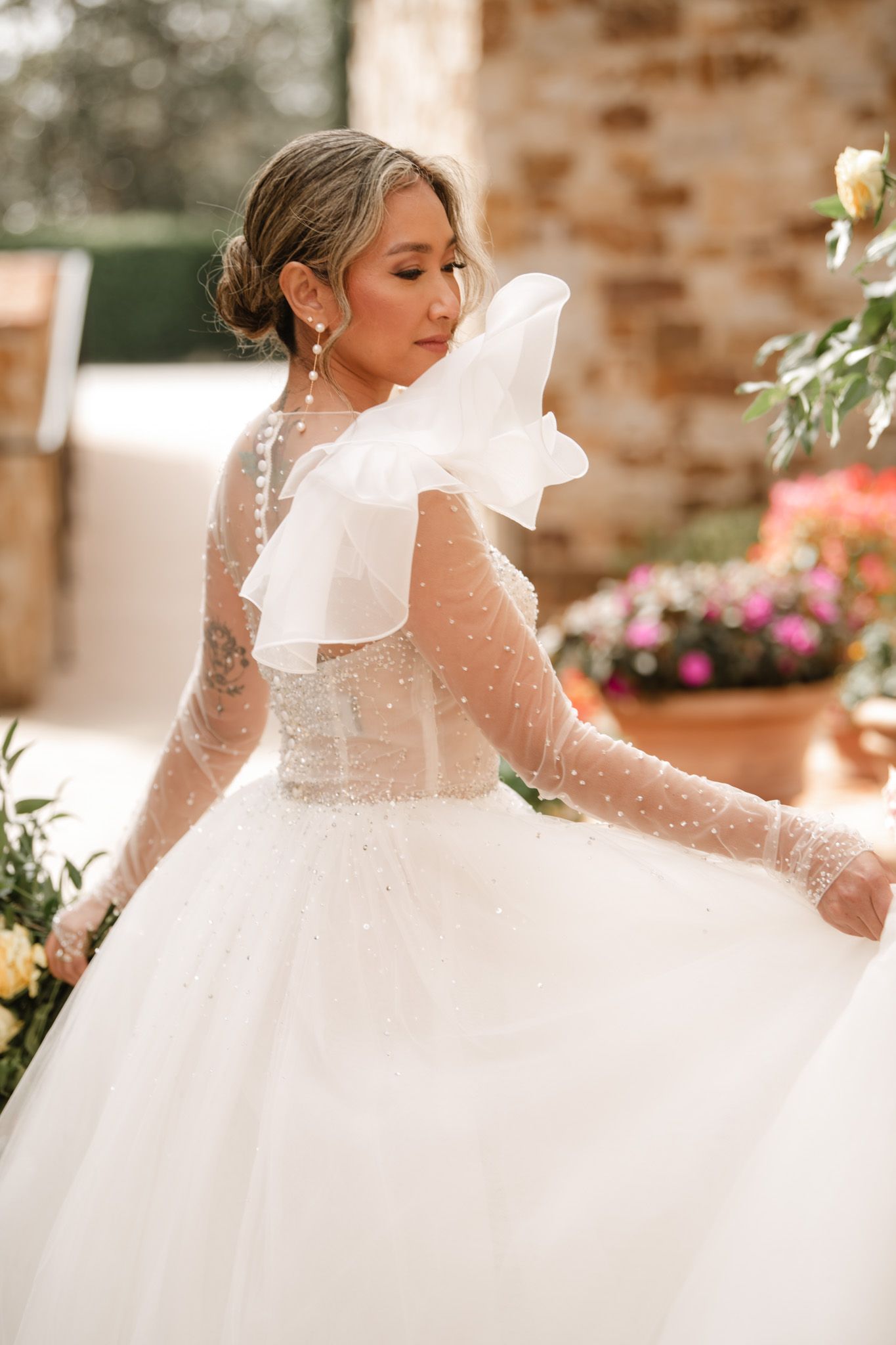 Ethereal wedding dress details featuring sheer lace sleeves and flowing white fabric.
