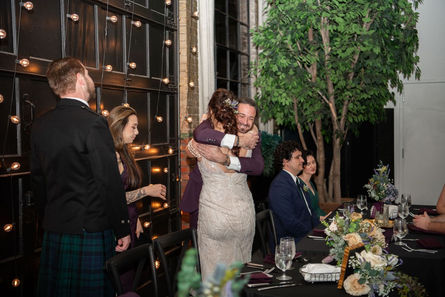 Wedding celebration in an industrial venue with string lights and natural greenery accents.