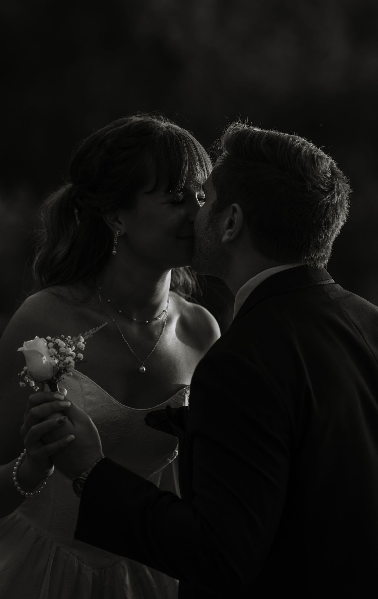 Dramatic low-light portrait of newlyweds sharing an intimate moment.