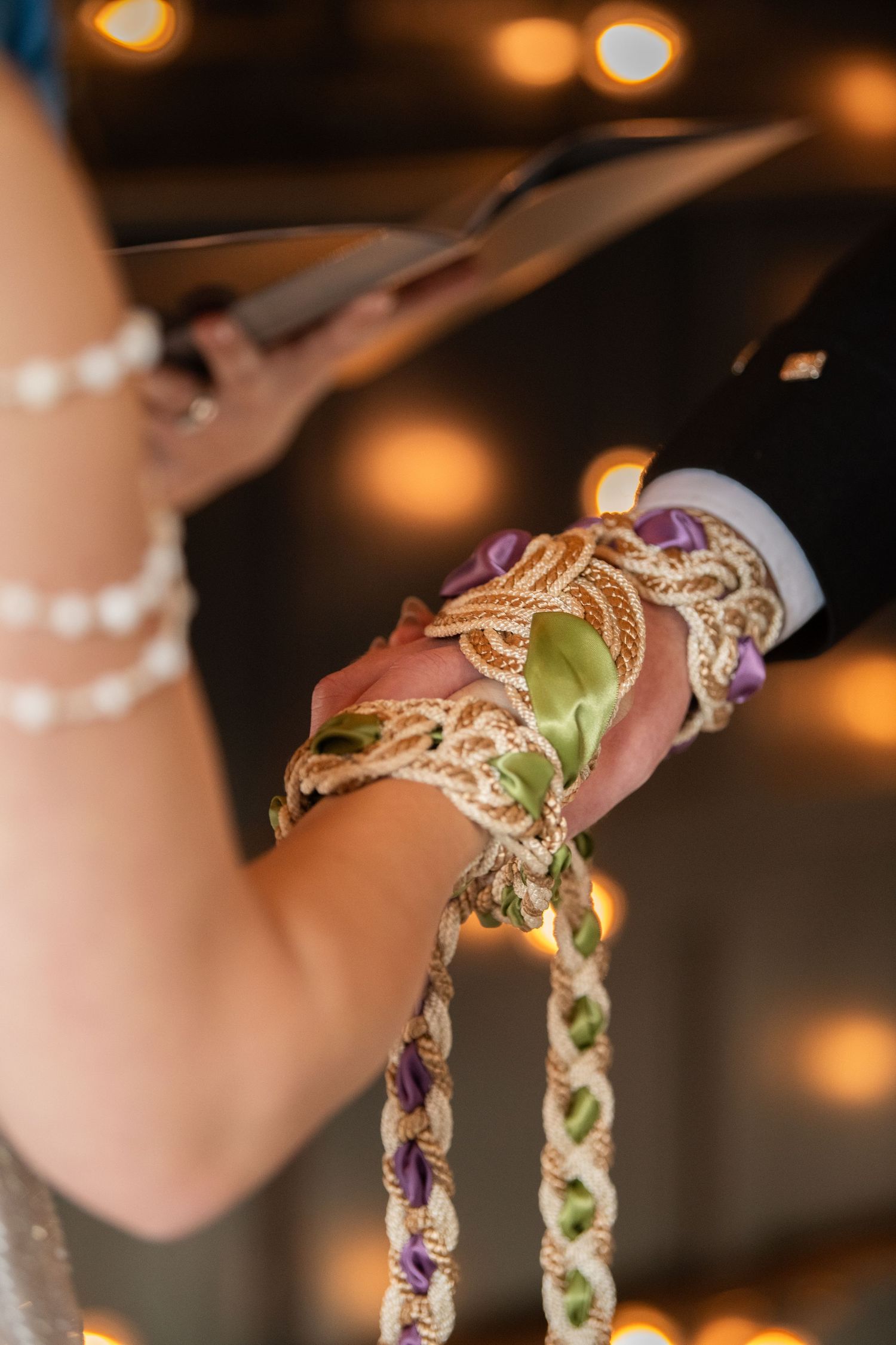 Detail shot of intricate braided handfasting cords with purple and green accents.