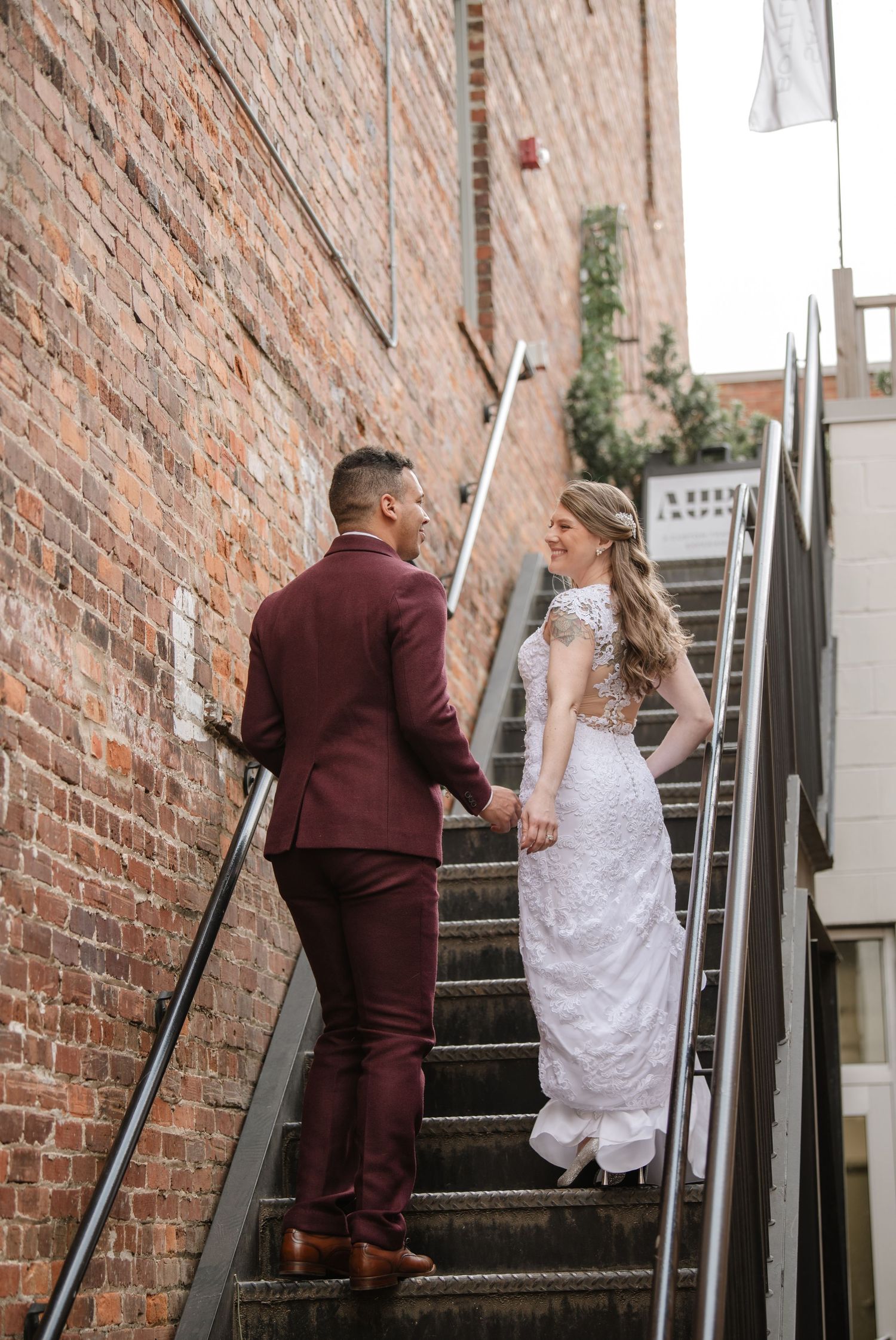 Wedding couple ascends brick staircase together during their photo session.