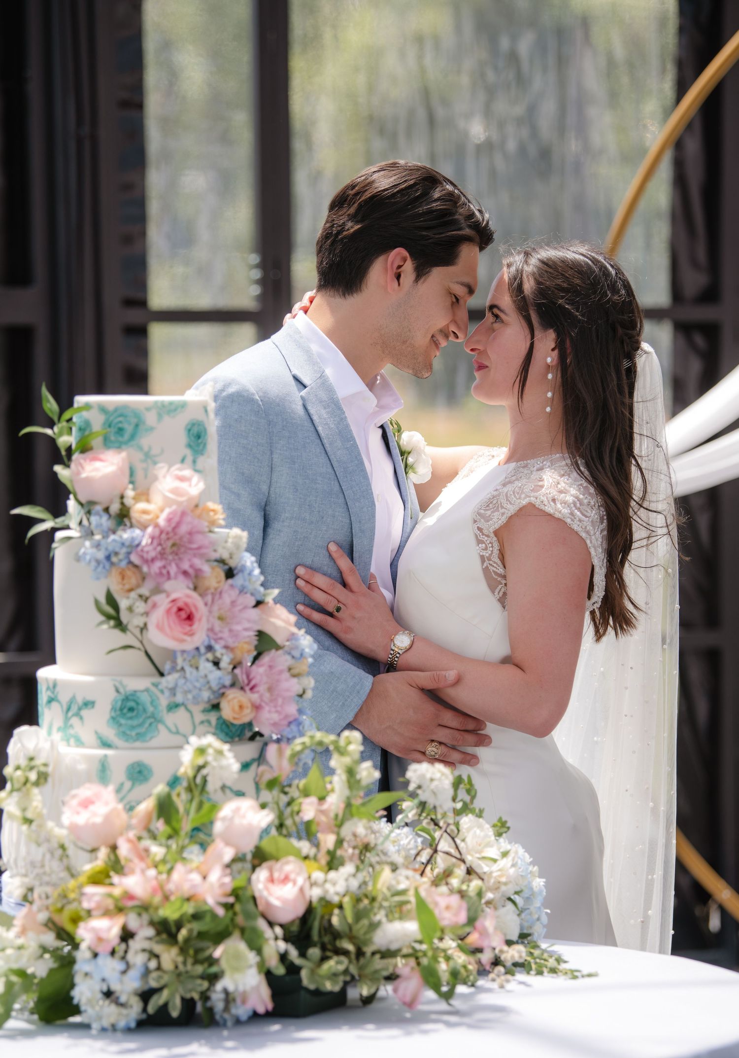 A romantic wedding scene with a couple embracing outdoors surrounded by elegant floral arrangements in pink and white.