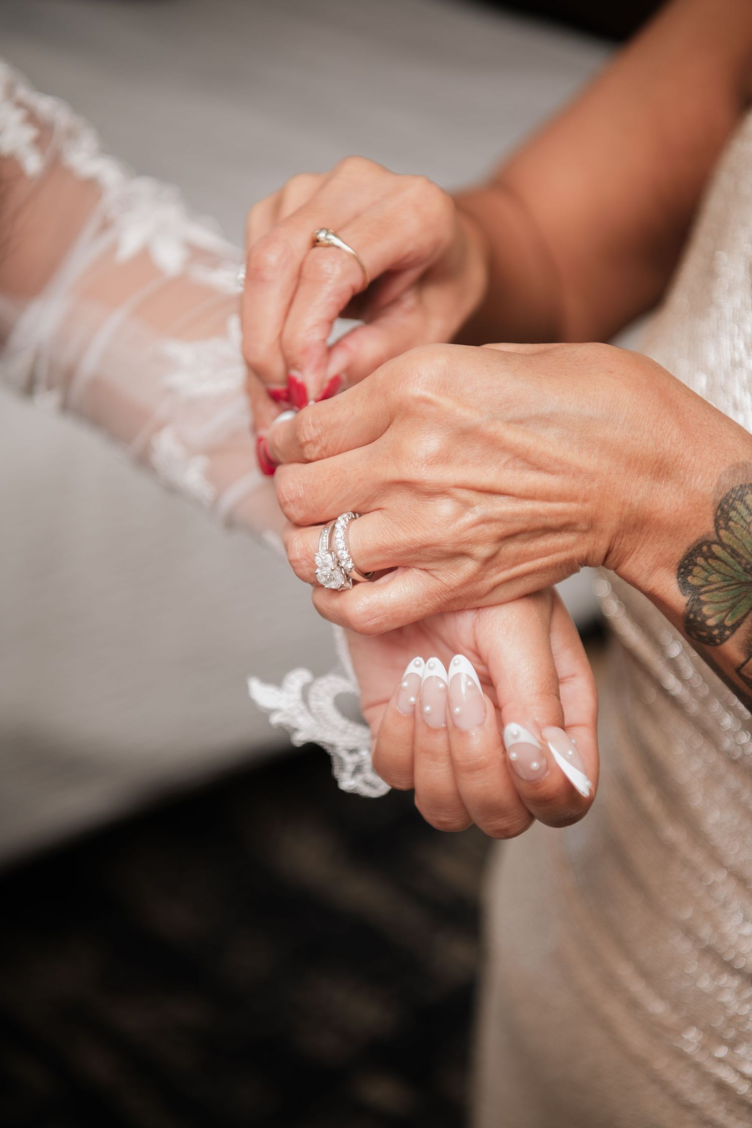 Close-up of hands exchanging rings with delicate lace dress details visible.