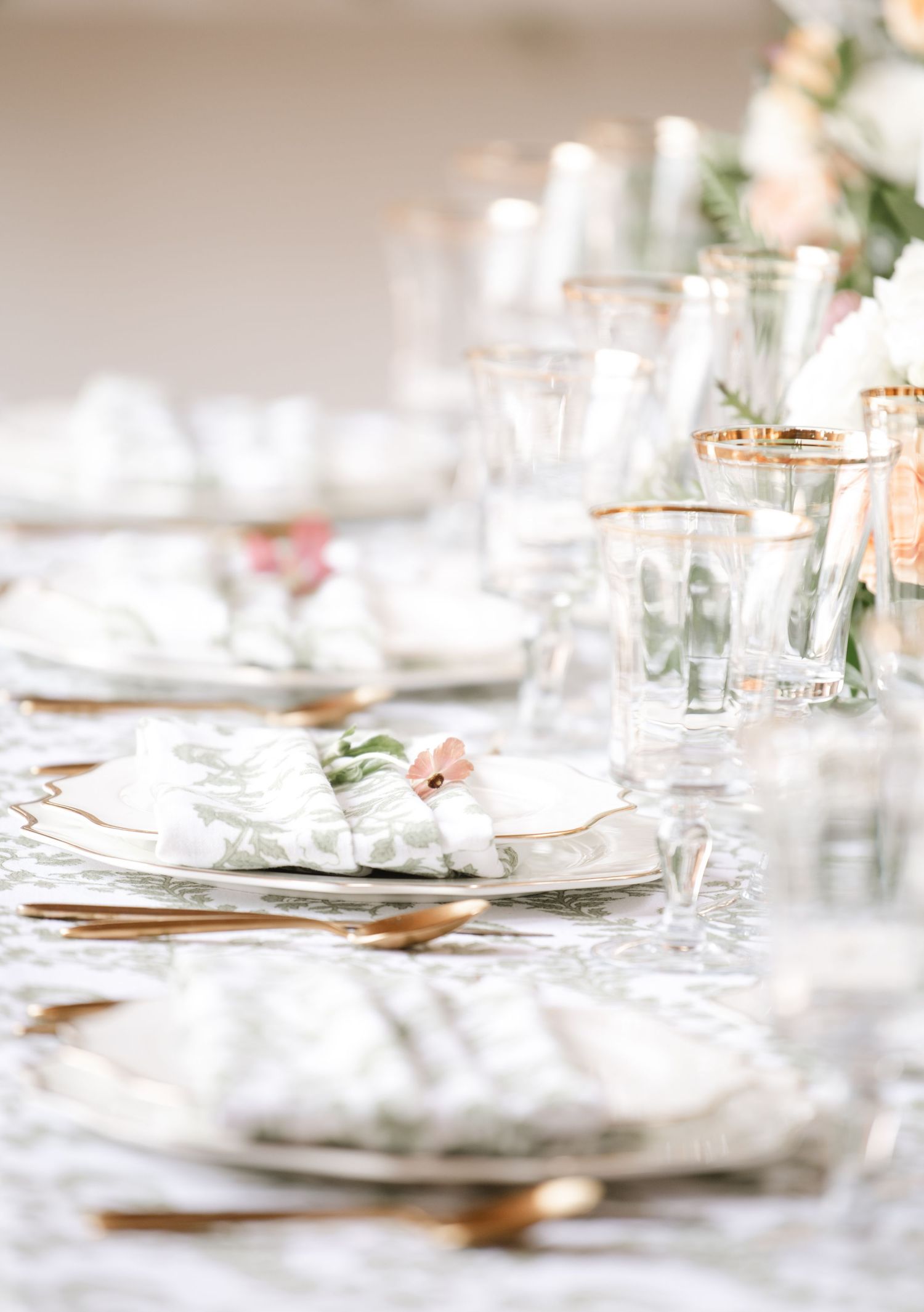 Elegant wedding table settings with white linens and gold accents in soft focus.