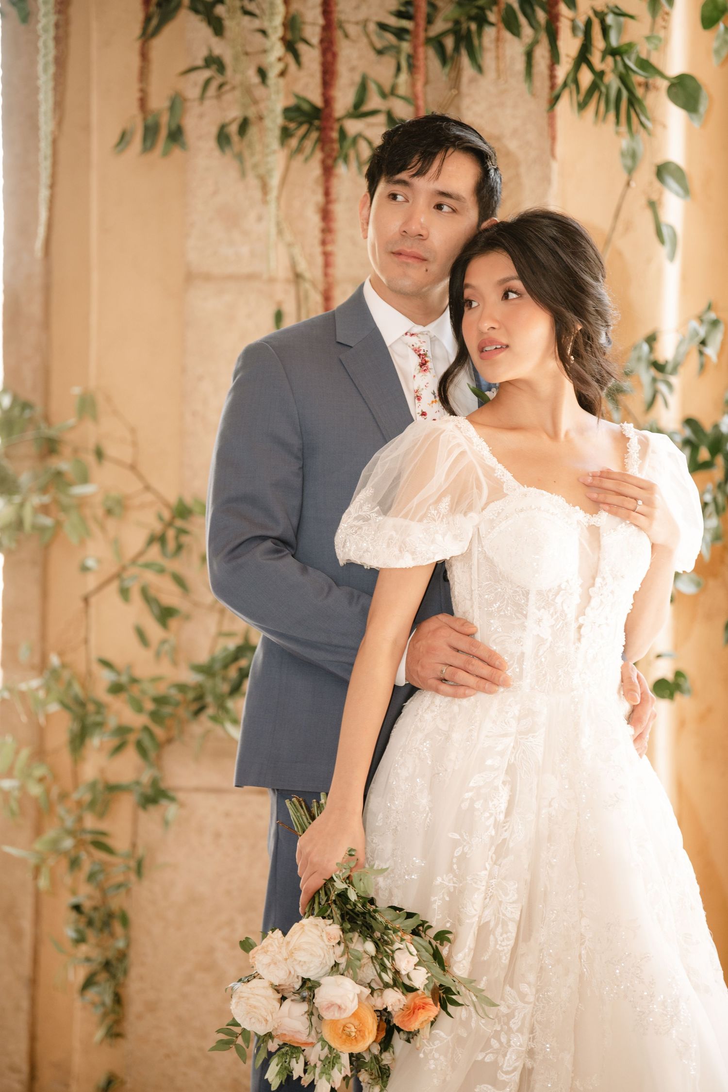 Romantic wedding portraits under stone archways decorated with cascading greenery.