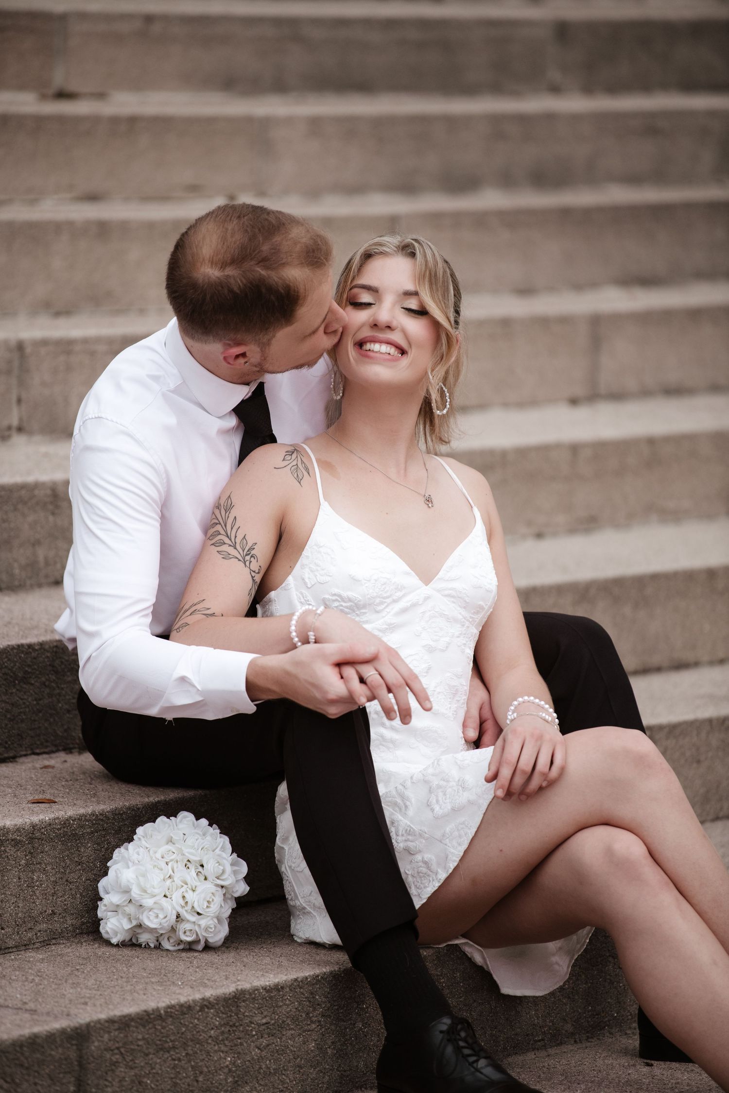 An intimate portrait of a couple in formal wear lounging on stone steps.