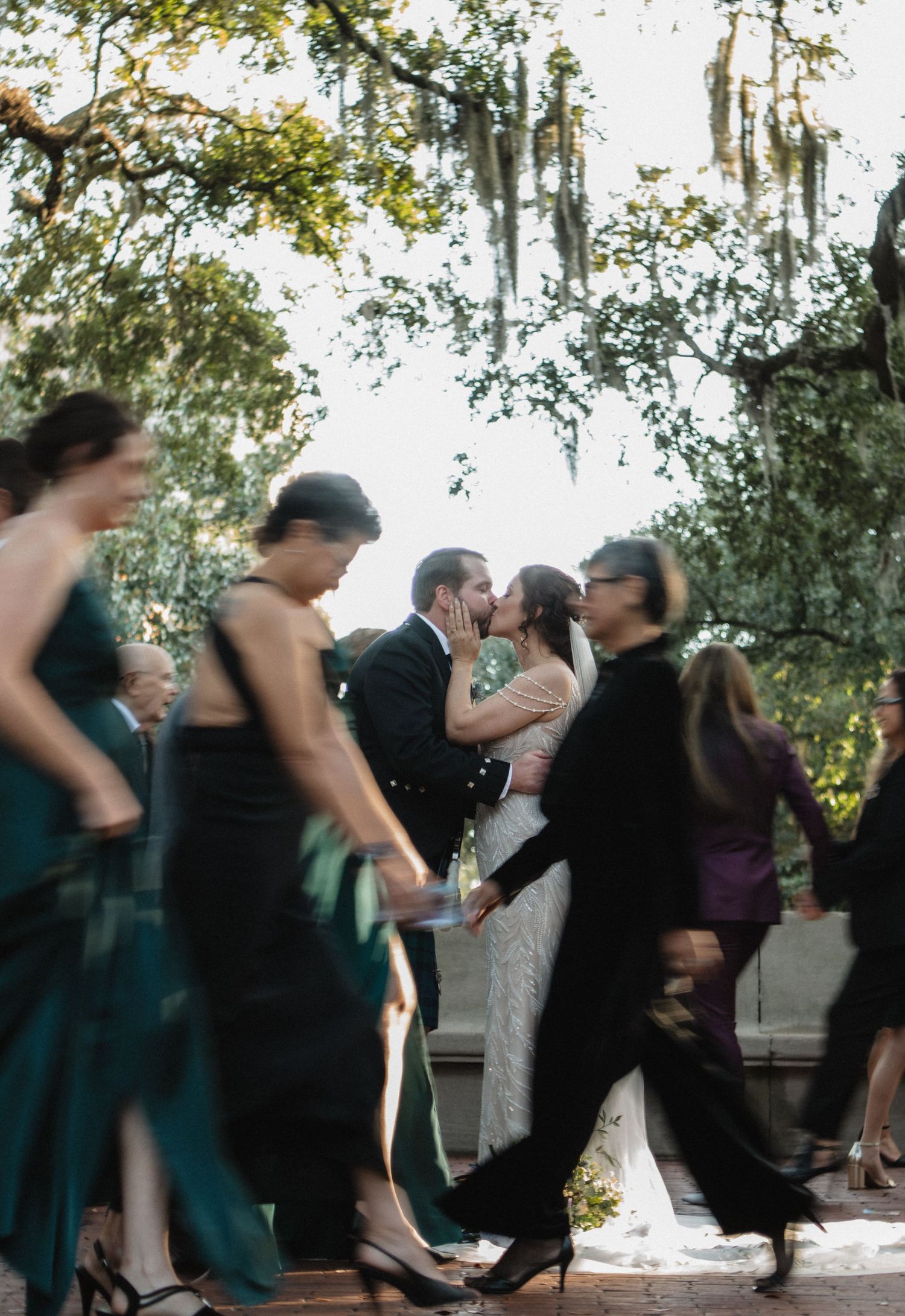 People dancing in motion blur at an outdoor wedding reception under trees.