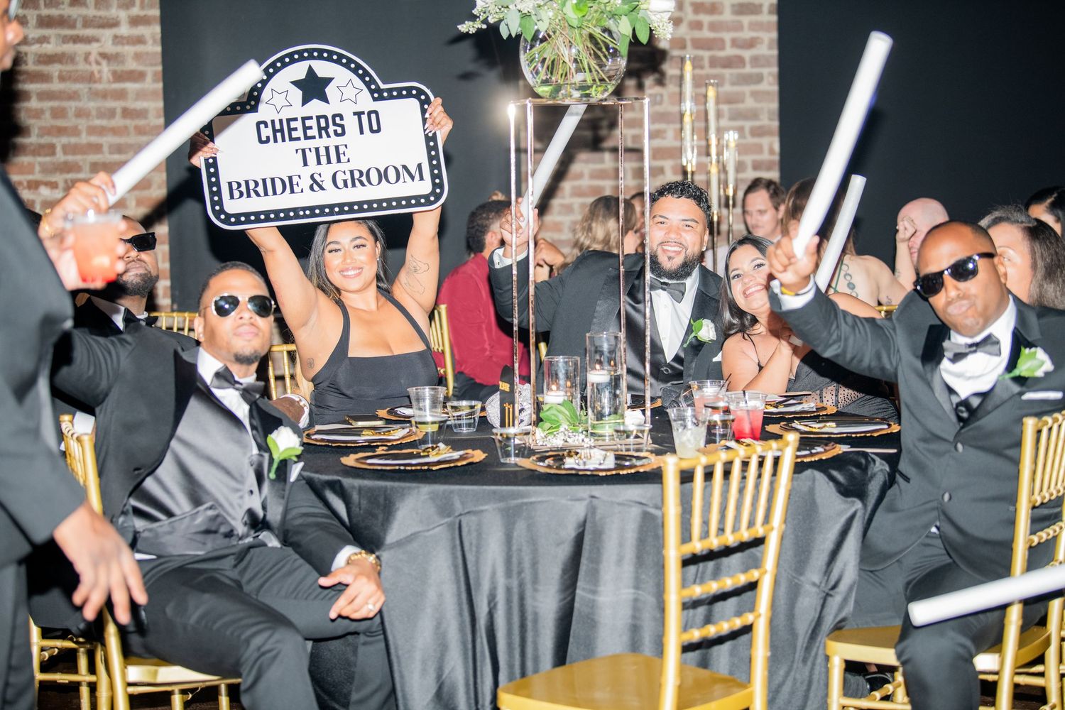 Wedding reception guests celebrating with fun props and signs at their table.