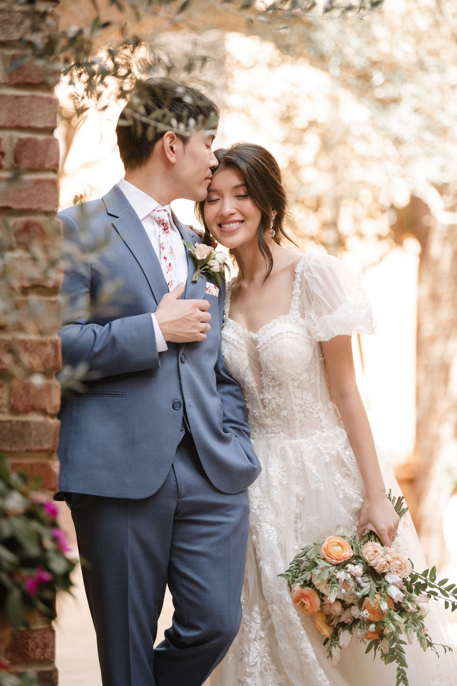 Intimate wedding couple photos showing tender moments in front of a brick wall with natural lighting.