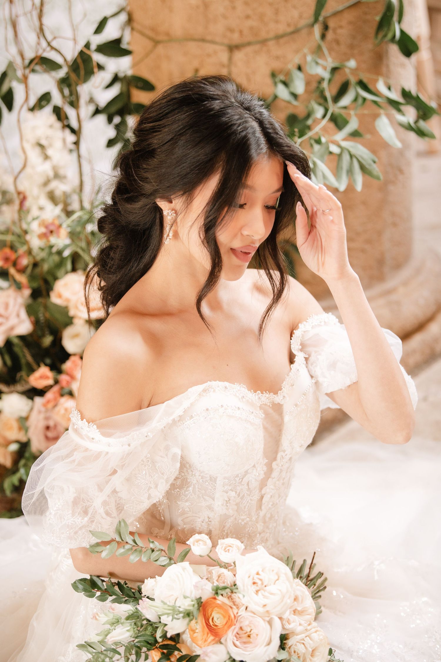 Romantic bridal scene with peach roses and olive branch decorations in soft natural light.