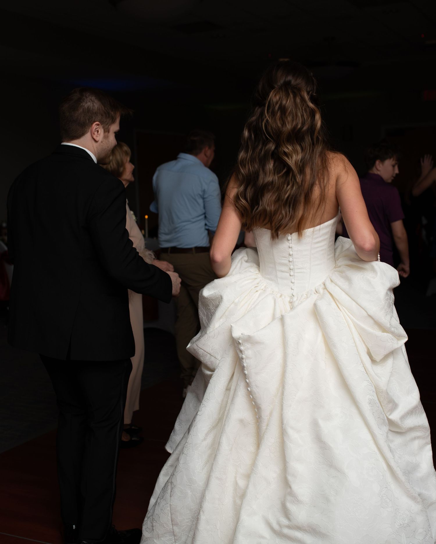 Back view of a bride in a white ballgown dancing at her wedding reception.