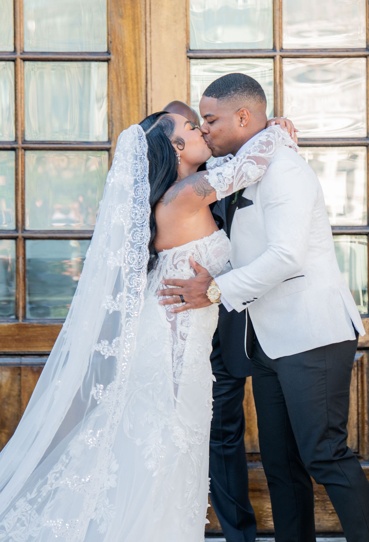 Romantic wedding kiss sequence captured against rustic brick backdrop.