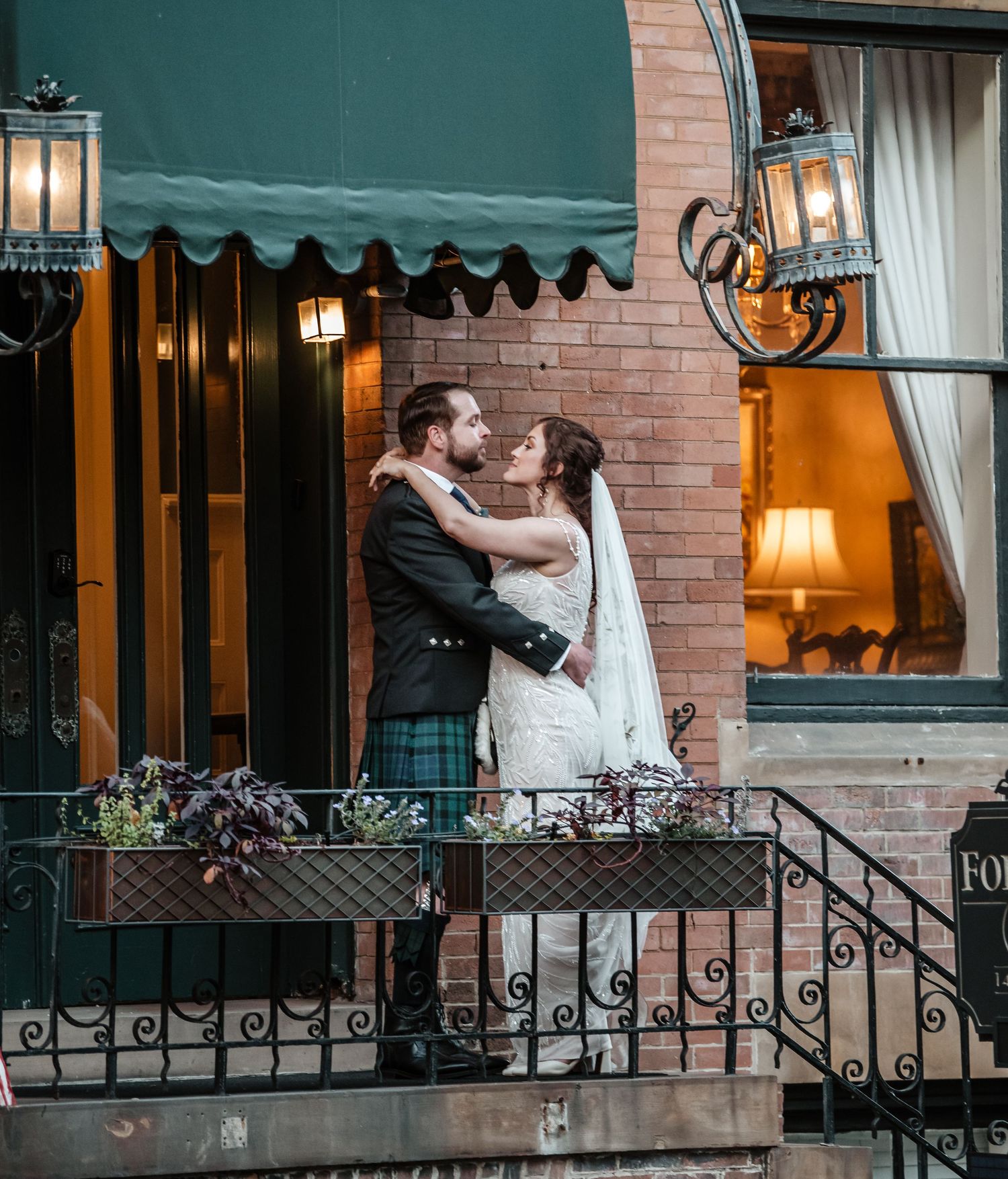 Wedding couple poses on the front steps of Foley House Inn at dusk.