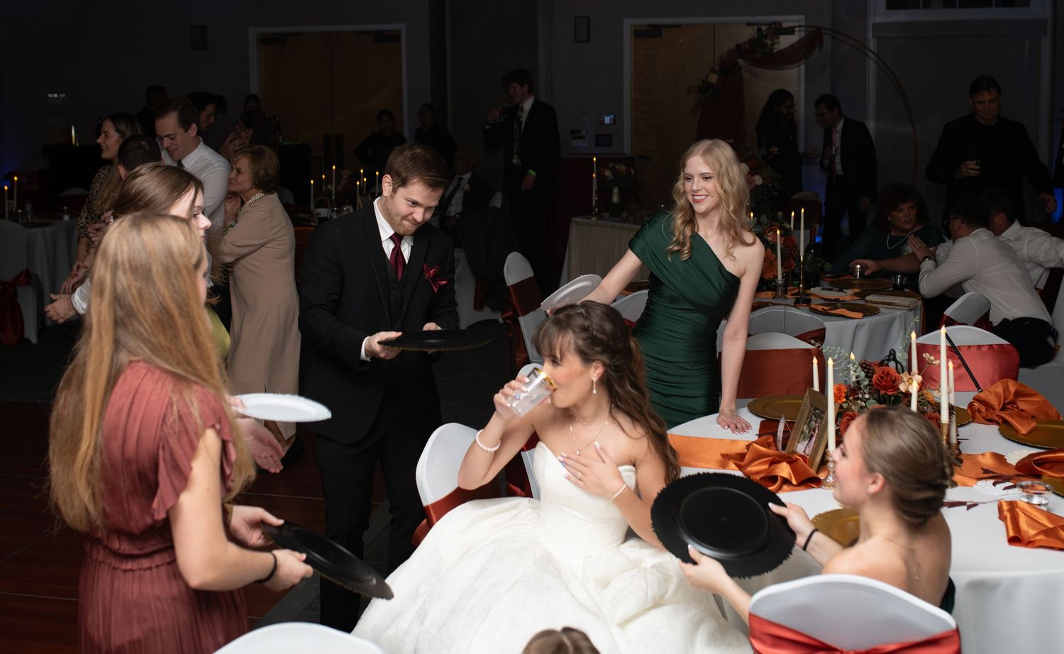 Wedding reception dinner scene with guests seated at decorated tables.