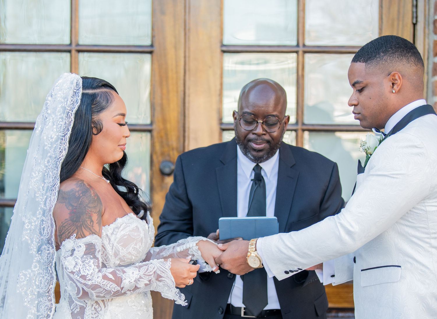 Wedding party members gather outside brick venue during ceremony.