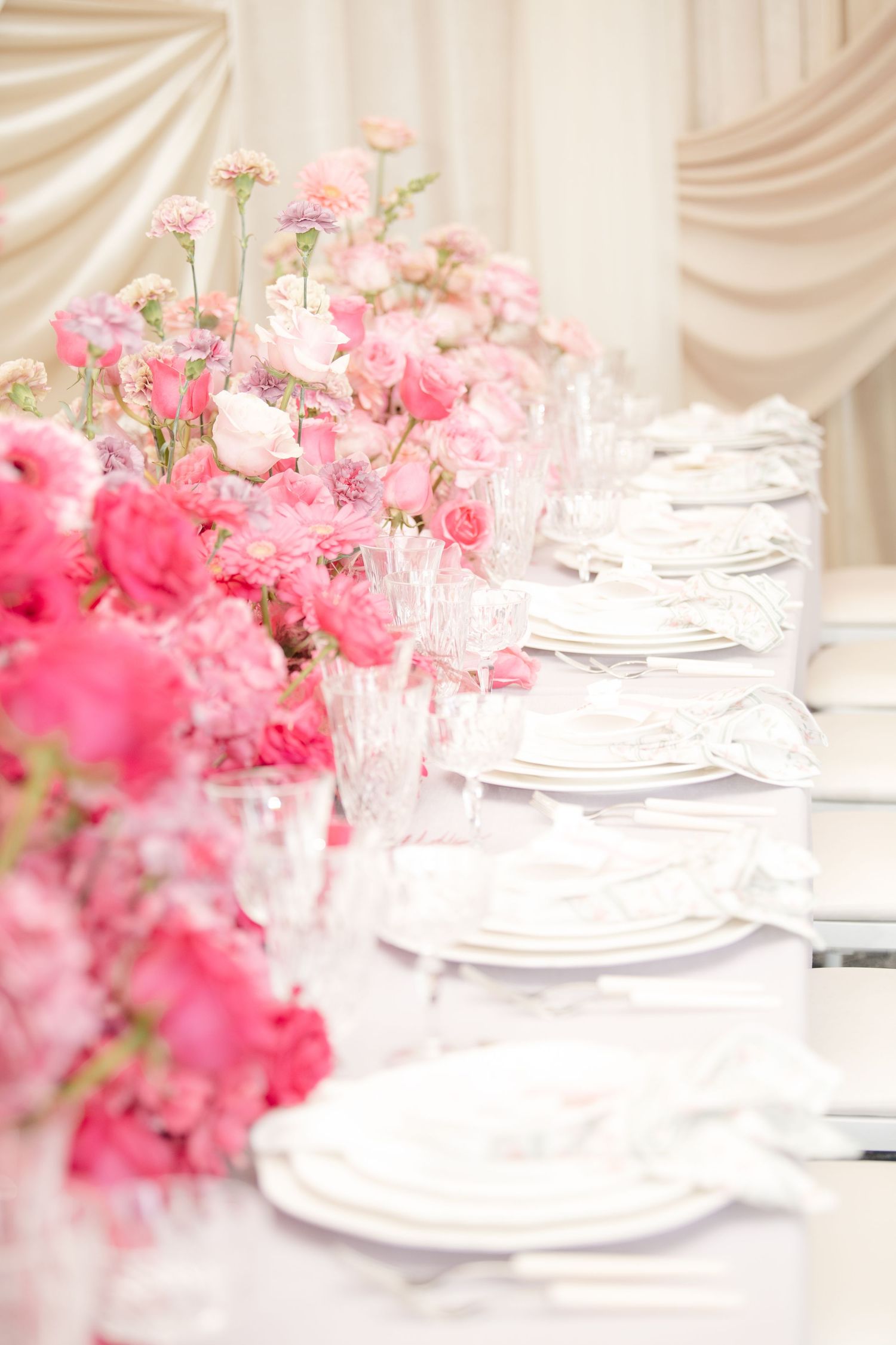 Elegant table setting with pink floral centerpieces and white place settings.