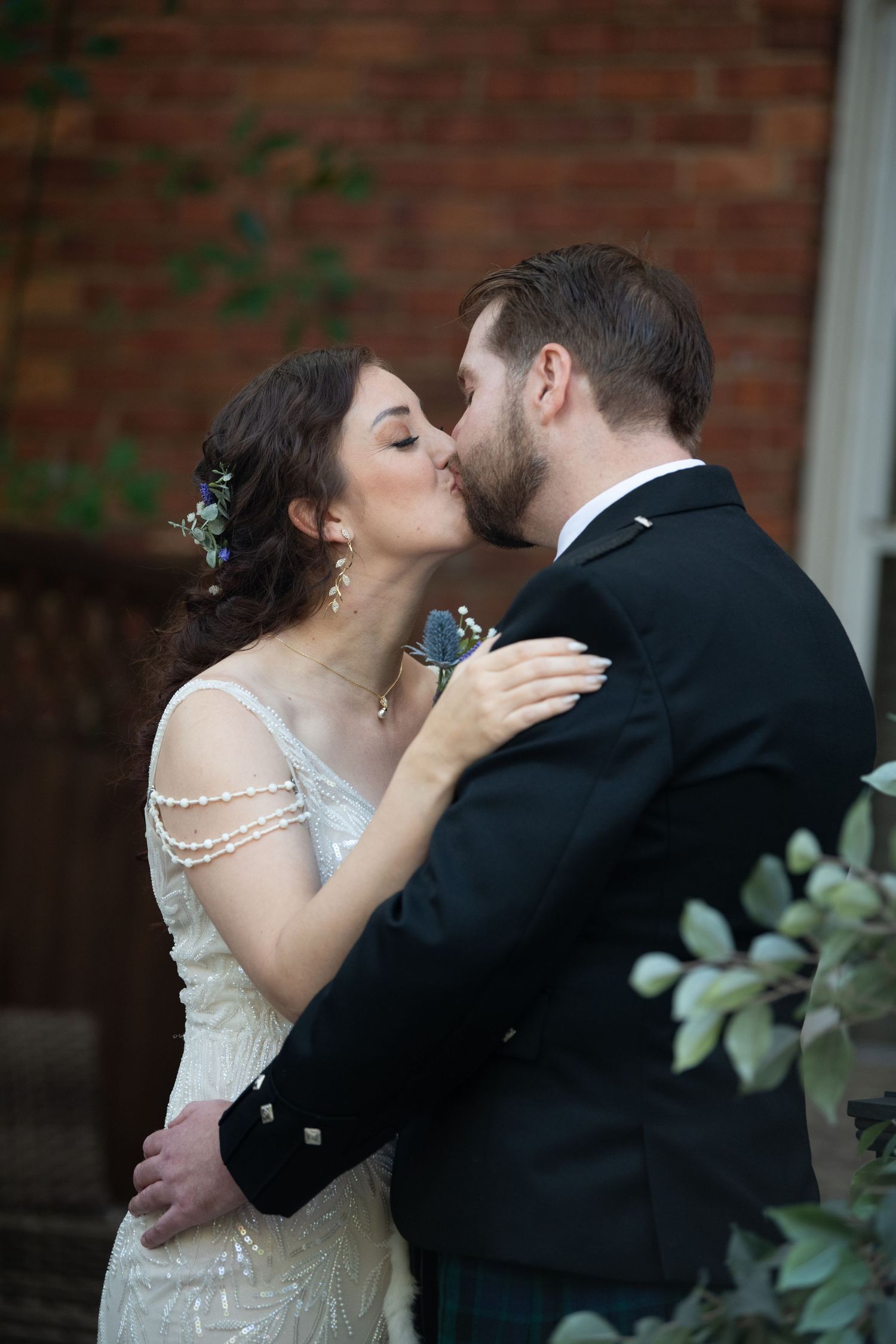 Intimate wedding portrait showing tender moment between couple against rustic brick background.