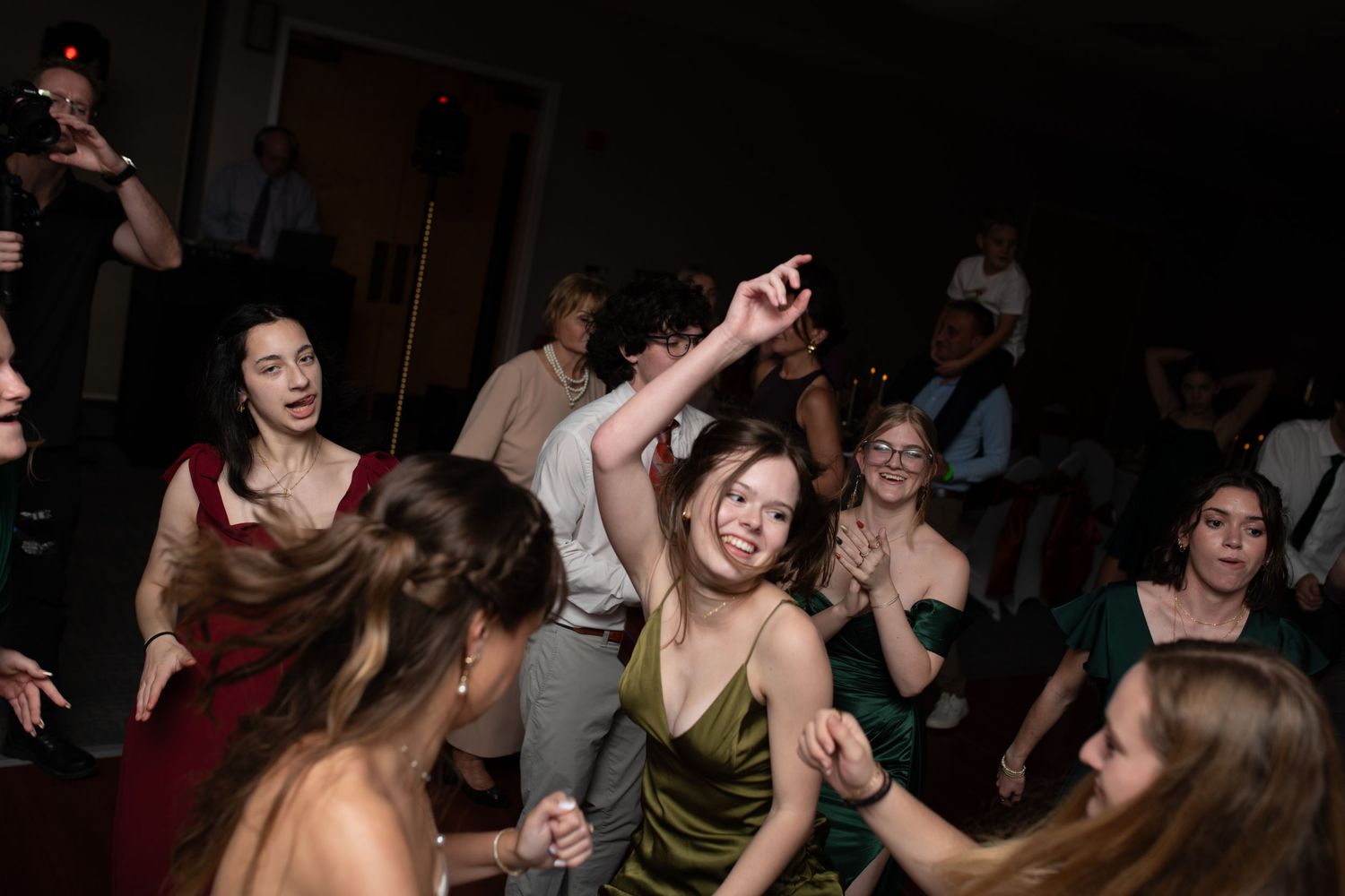 Guests dancing enthusiastically at a dimly lit wedding reception.