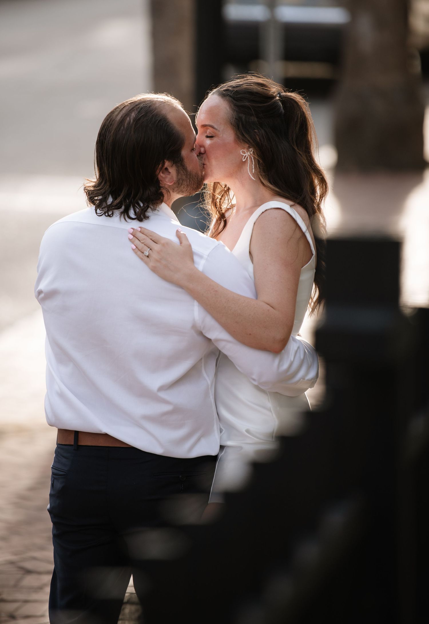 A romantic couple in white attire sharing an intimate dance together in a dimly lit setting.