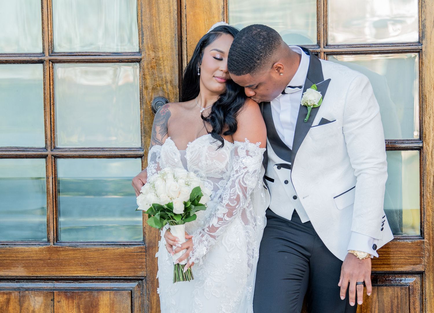 Intimate wedding couple portraits showing affection against rustic wooden door backdrop.