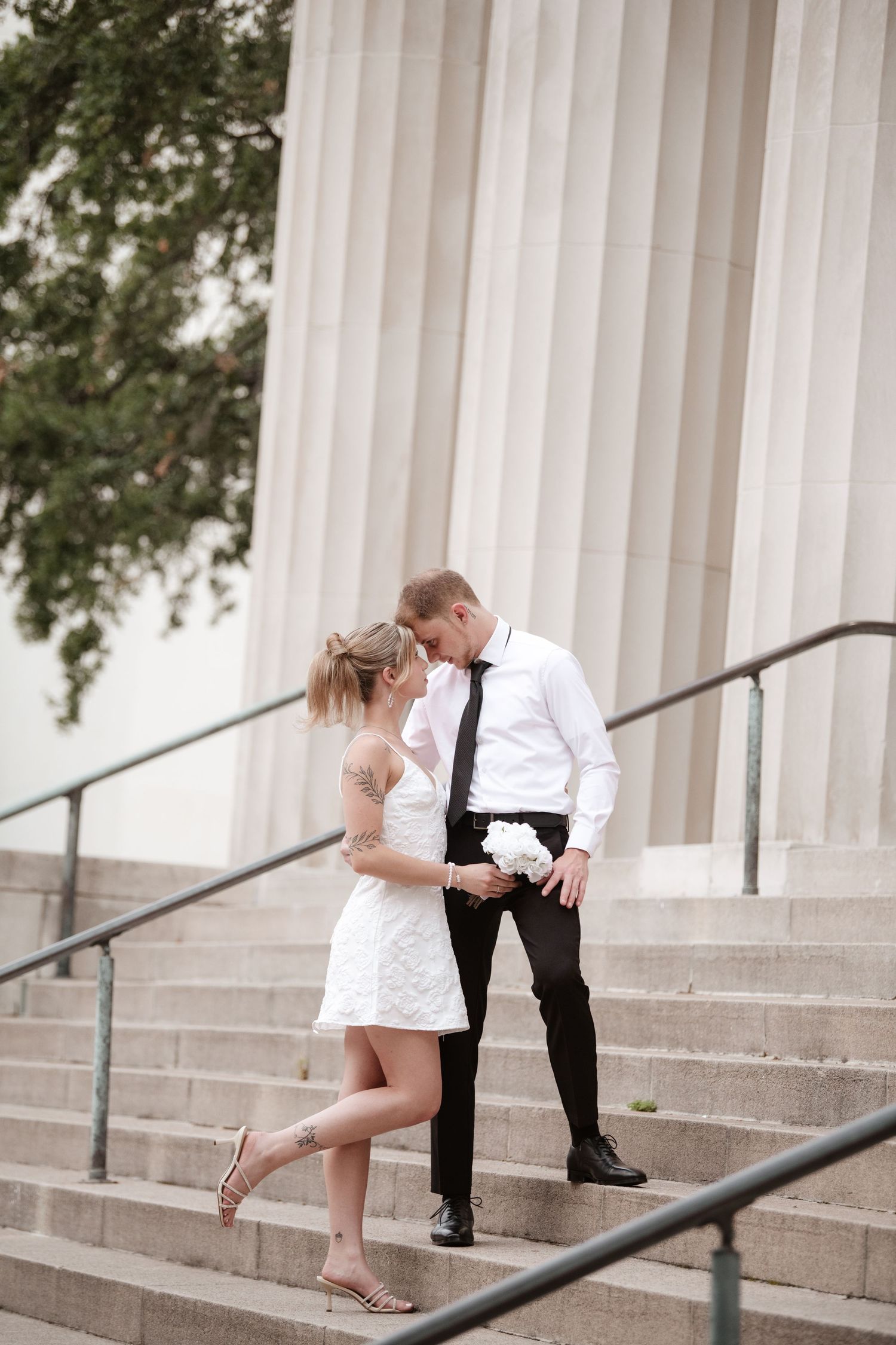 Couple performs playful dance sequence on grand stone staircase.