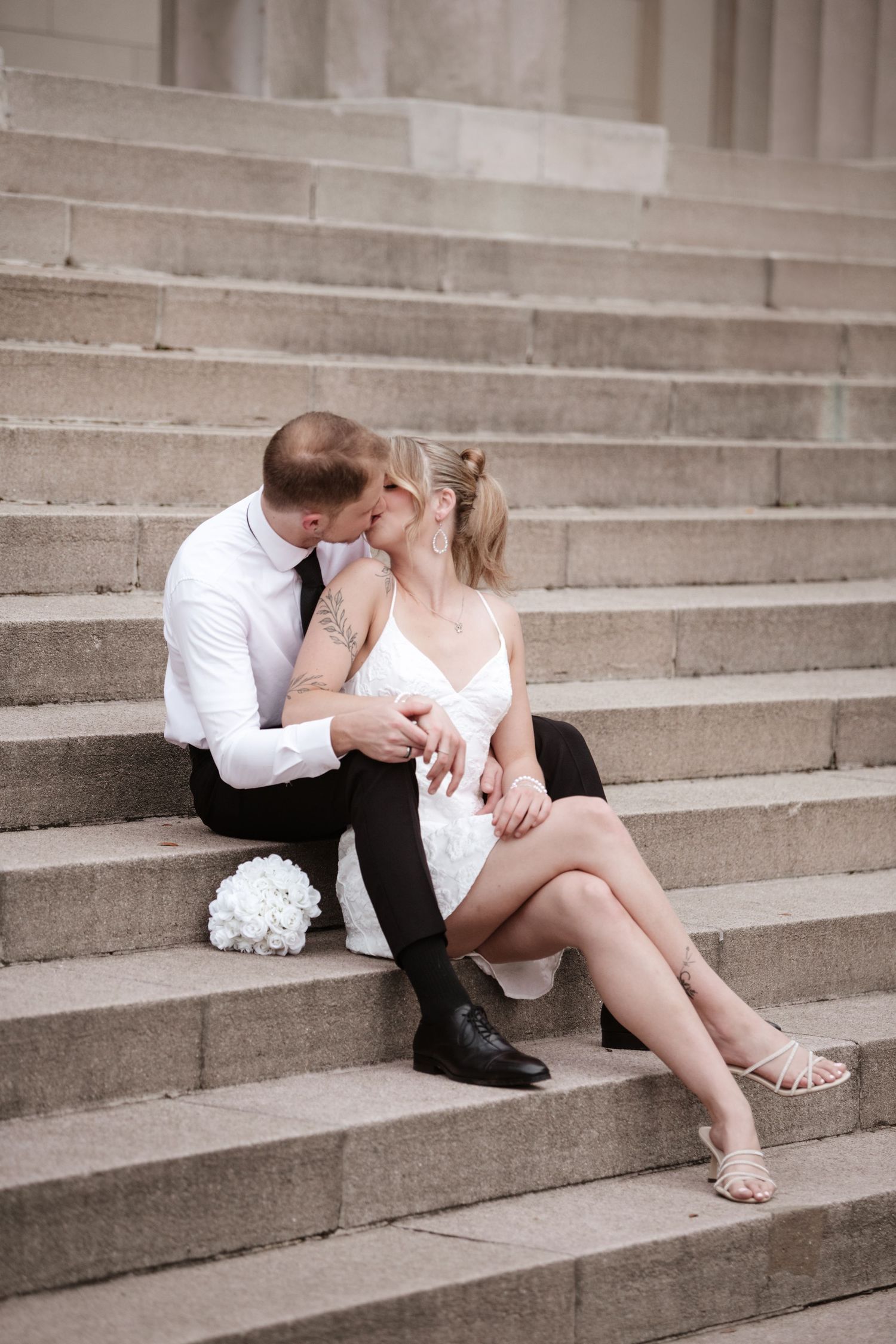 A tender moment between a couple sitting on wide stone steps.