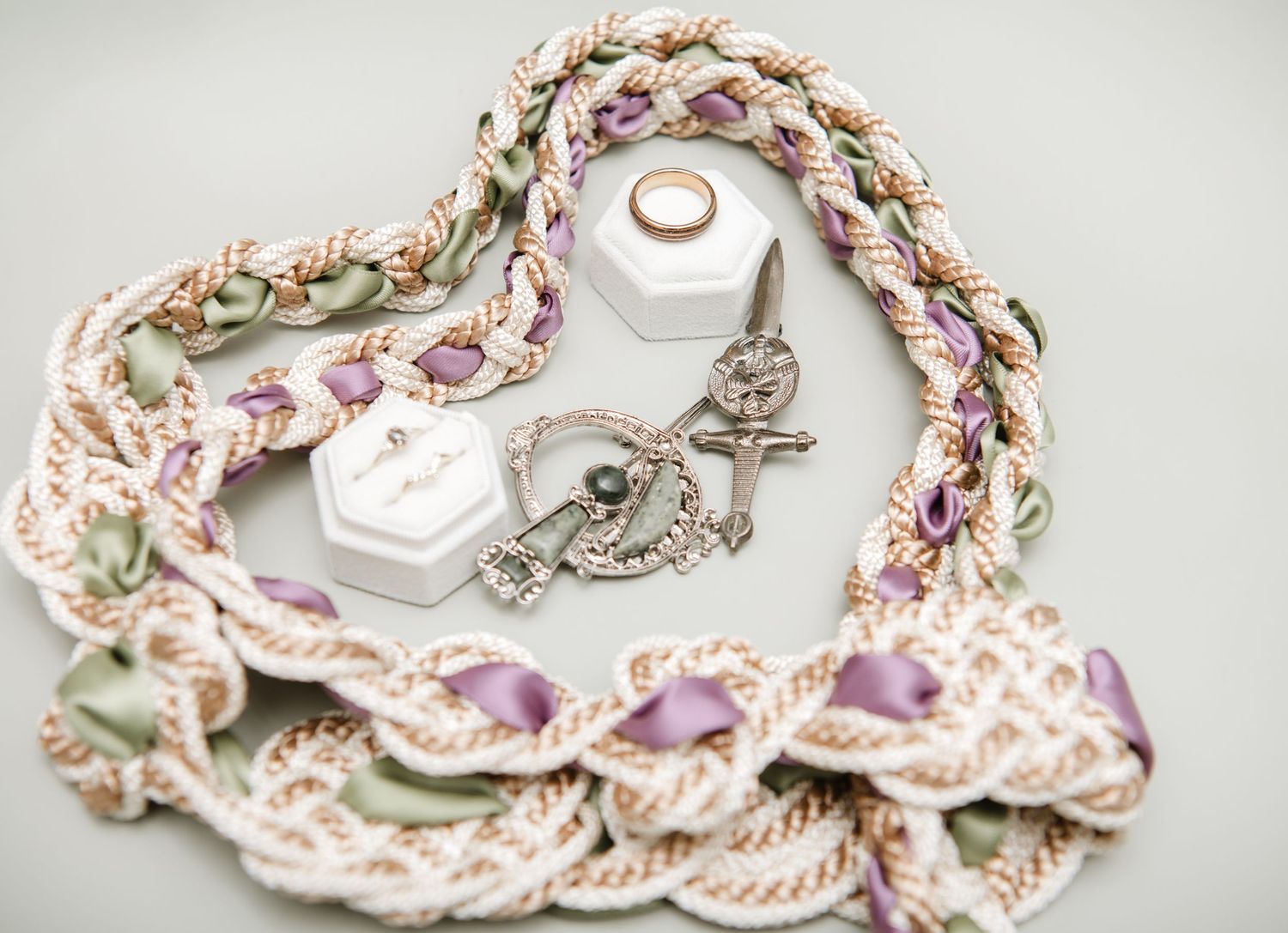 Delicate braided ribbon necklace with pink and white details arranged in a heart shape around white hexagonal boxes.