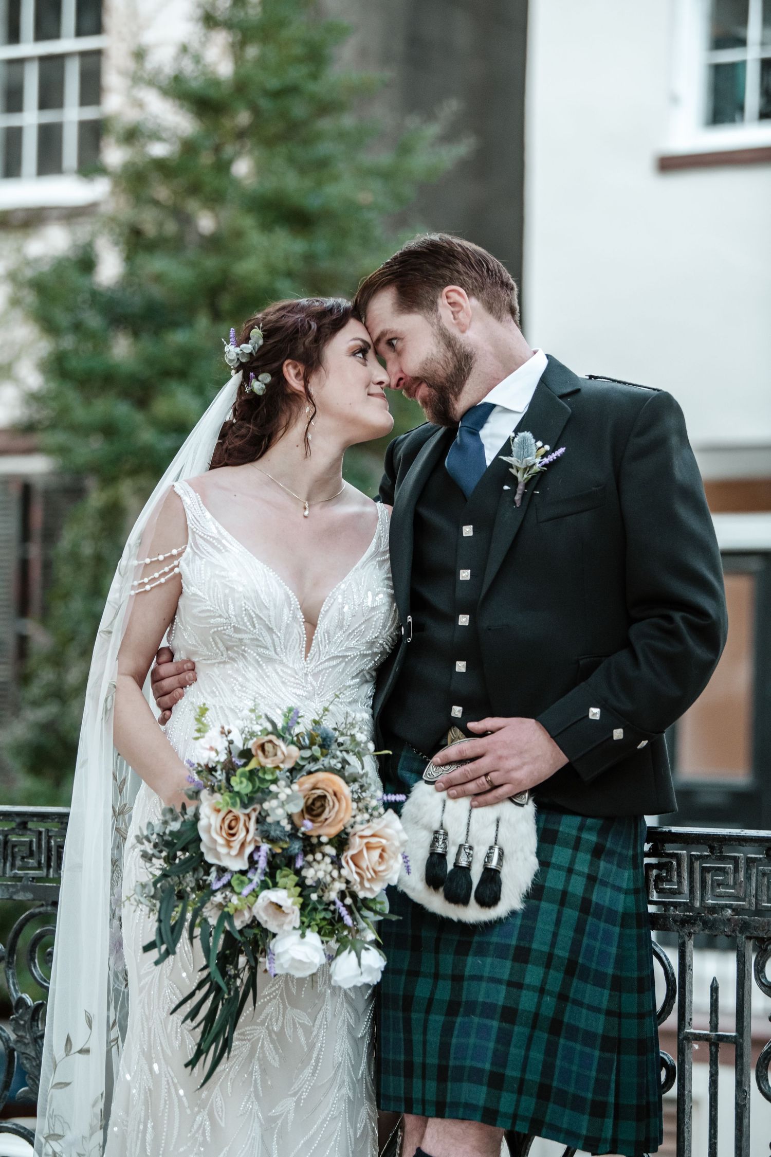 Romantic wedding portraits with bride holding floral bouquet and groom in traditional Scottish kilt.
