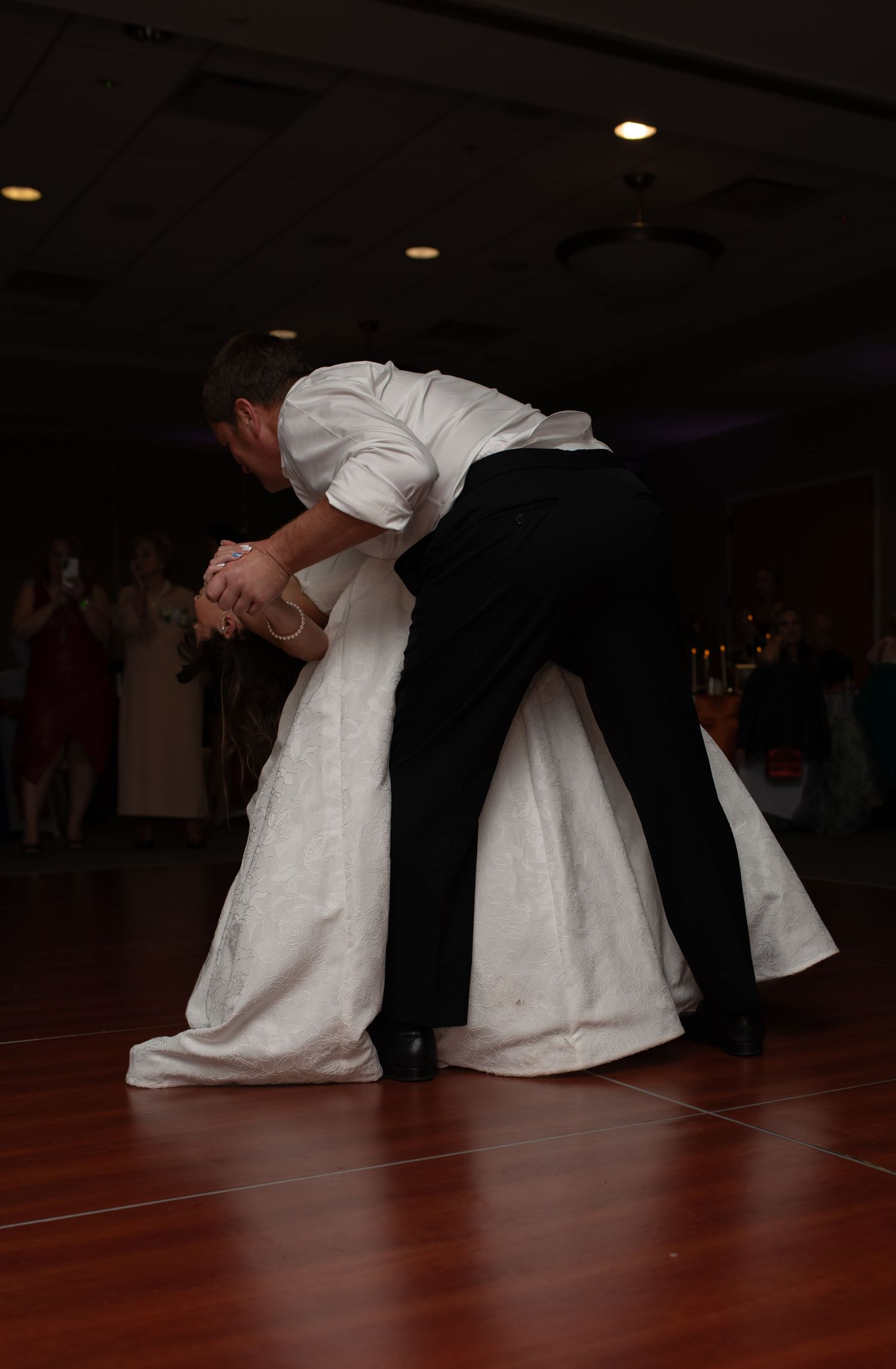 Couple performing dramatic dance moves on wooden floor in dim lighting.