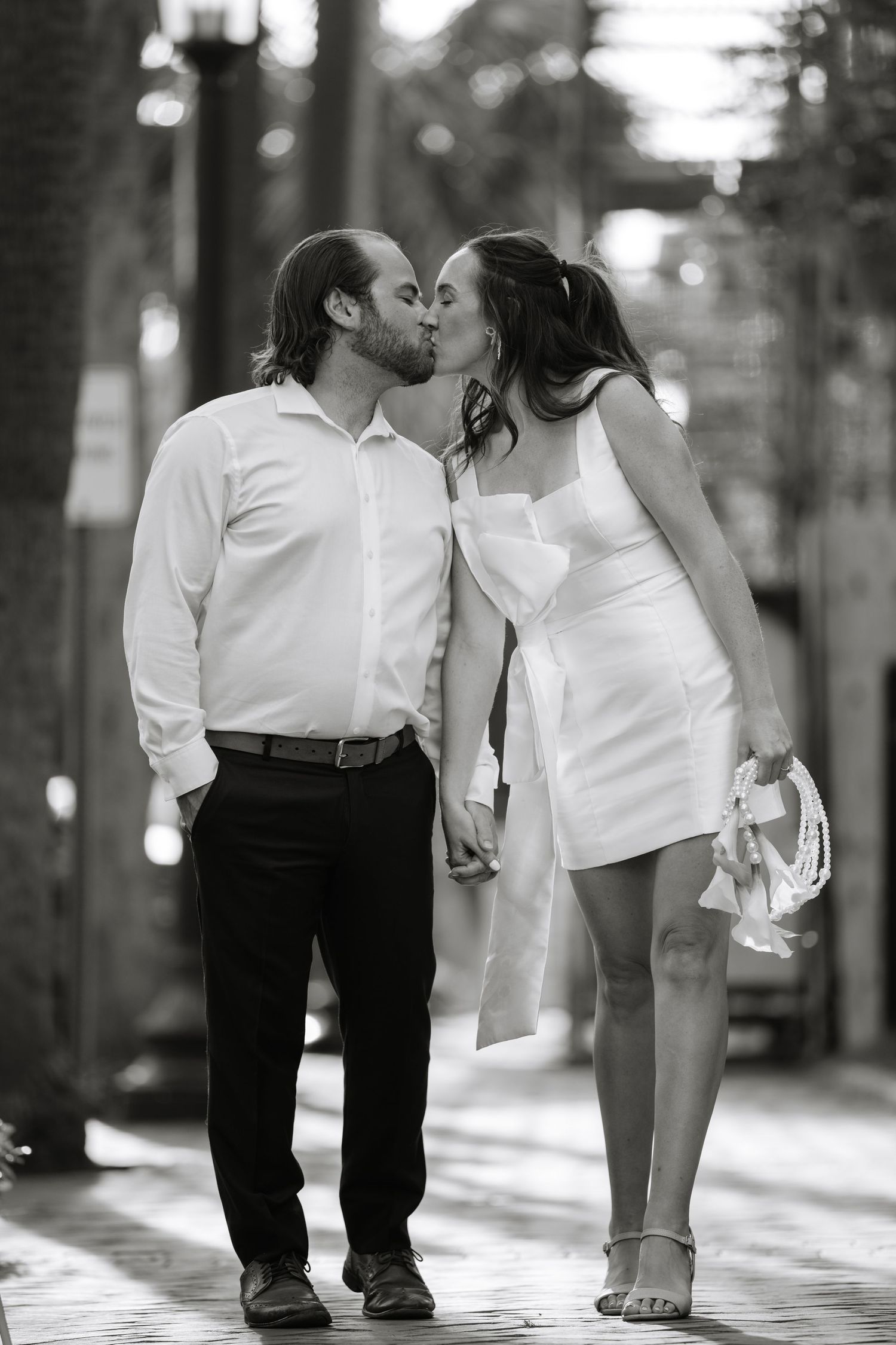 A couple shares a romantic kiss while walking together in a series of black and white photographs.