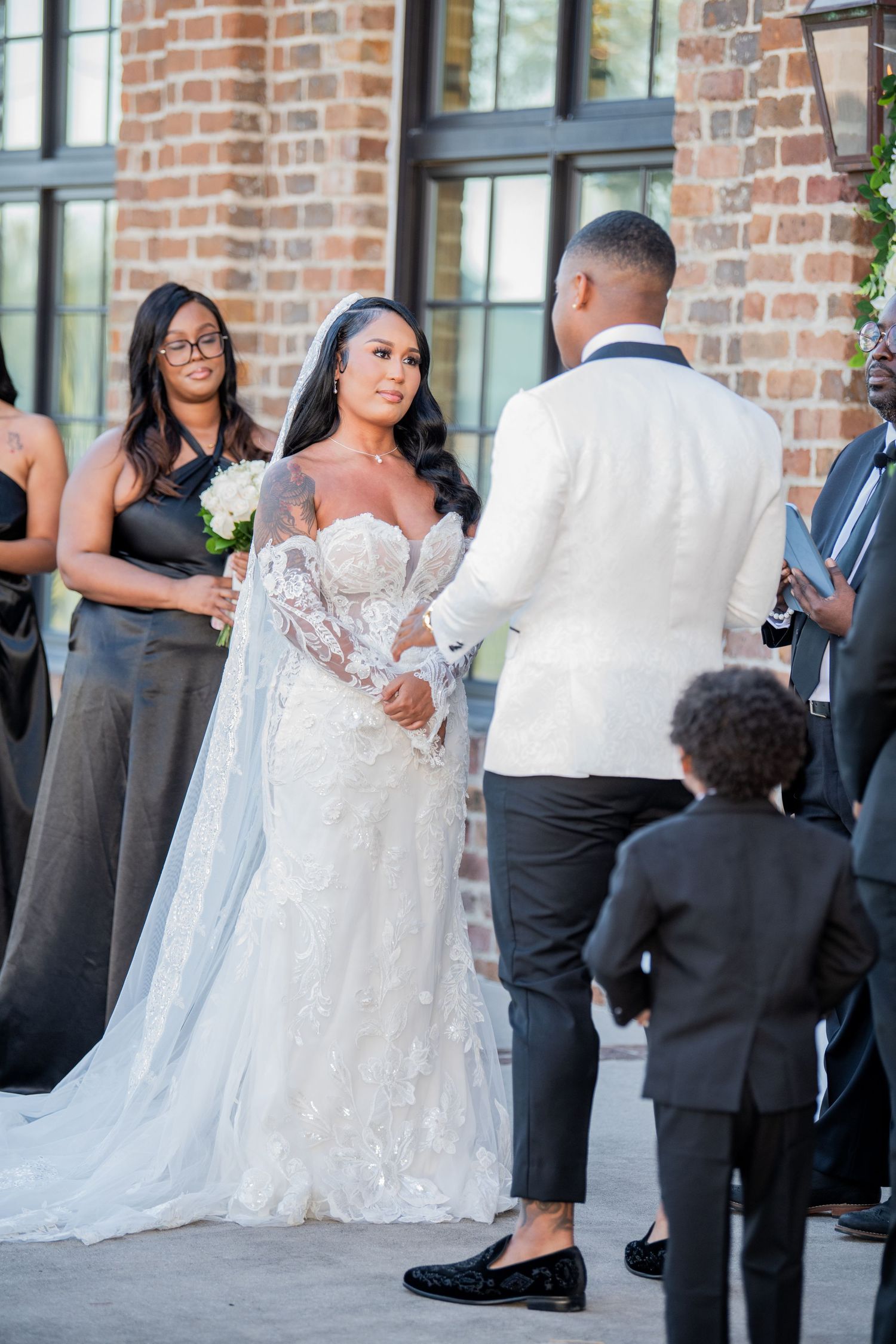Candid wedding moments captured outside brick venue with bridal party in formal attire.