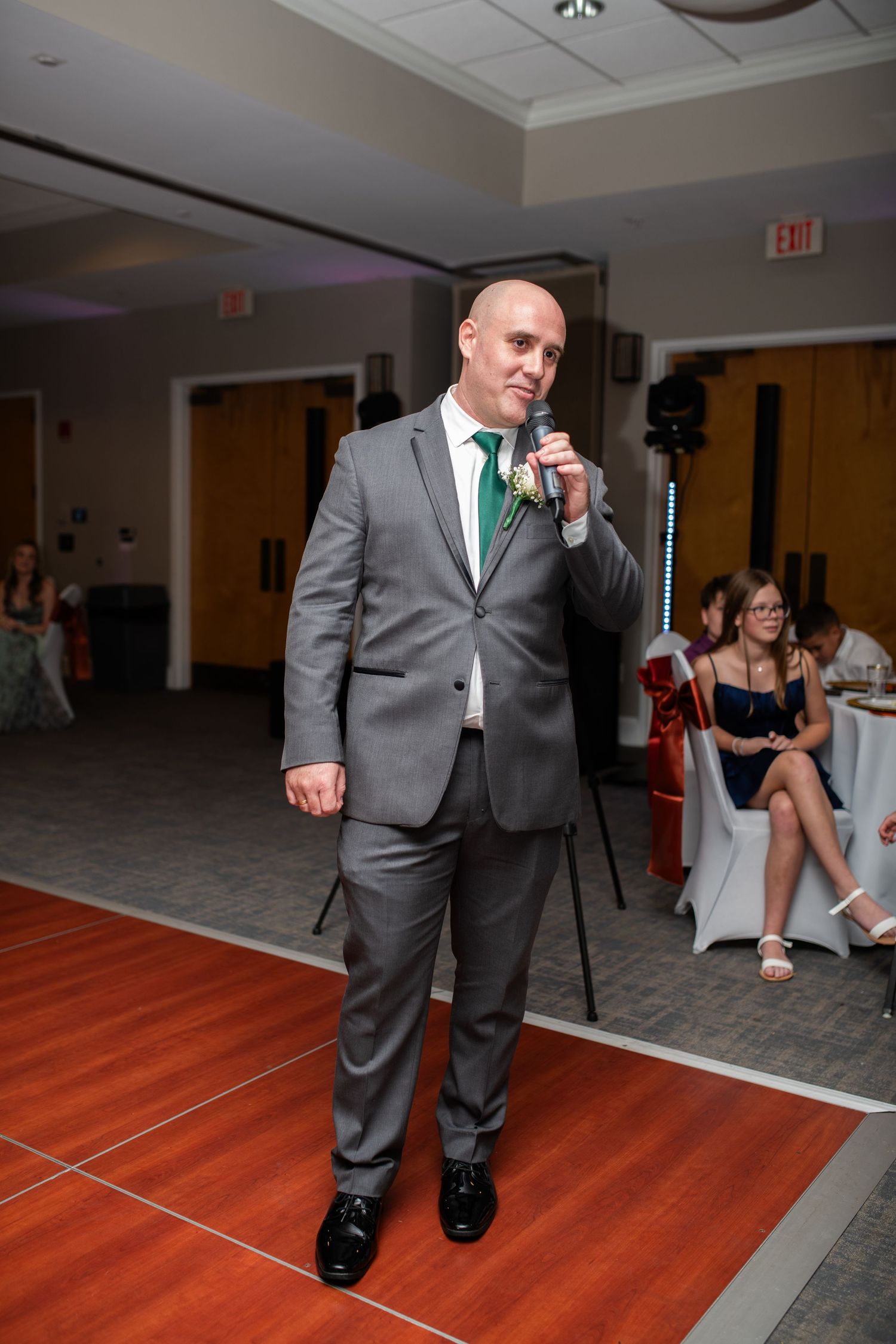 Person in grey suit performing on wooden dance floor at reception.