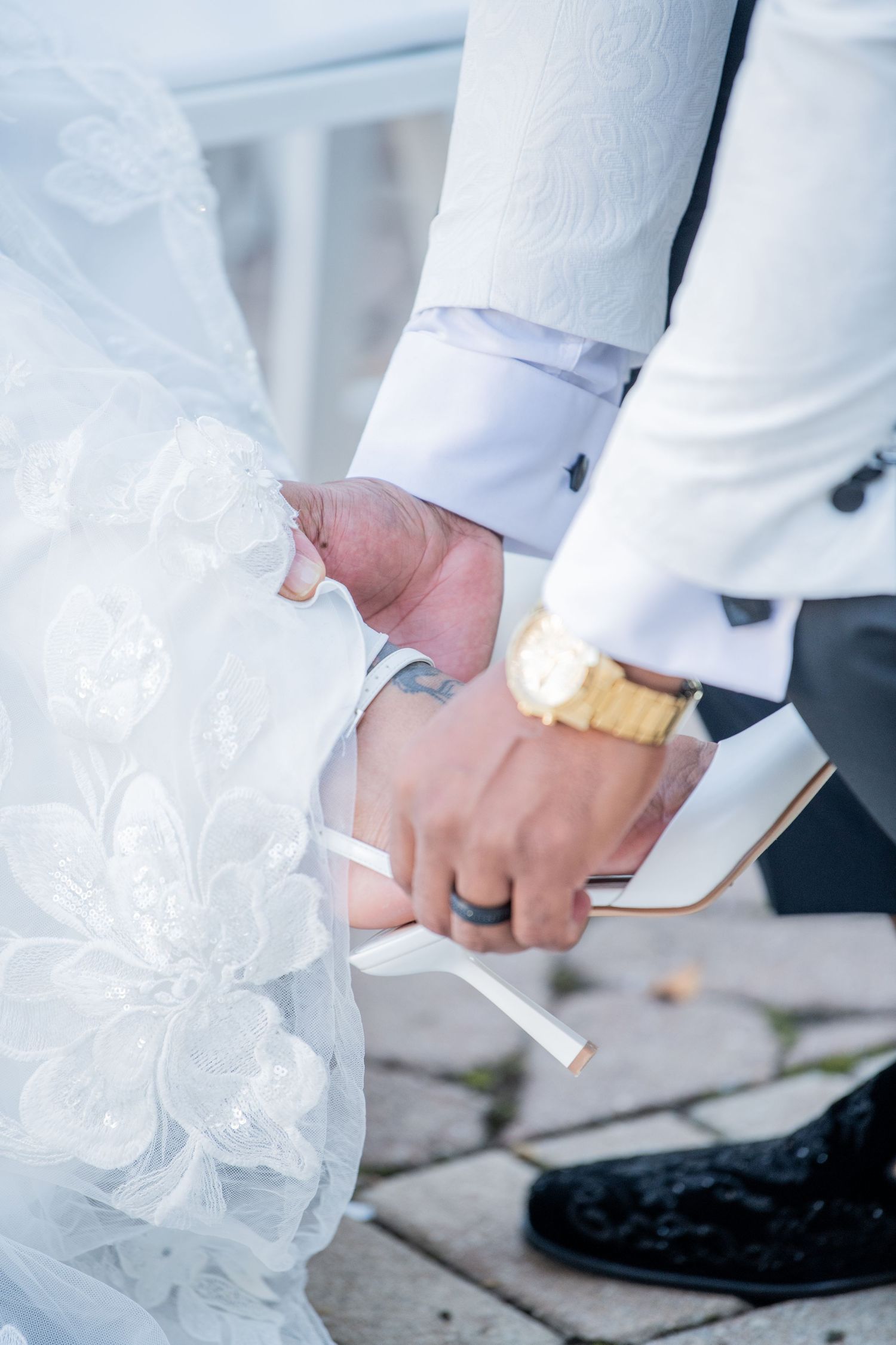 Close-up details of wedding attire showing lace dress and formal white suit.