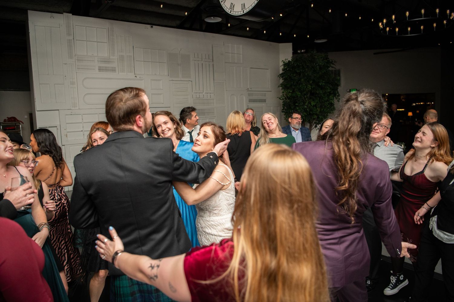 Lively dance party at a wedding reception with guests in formal attire.