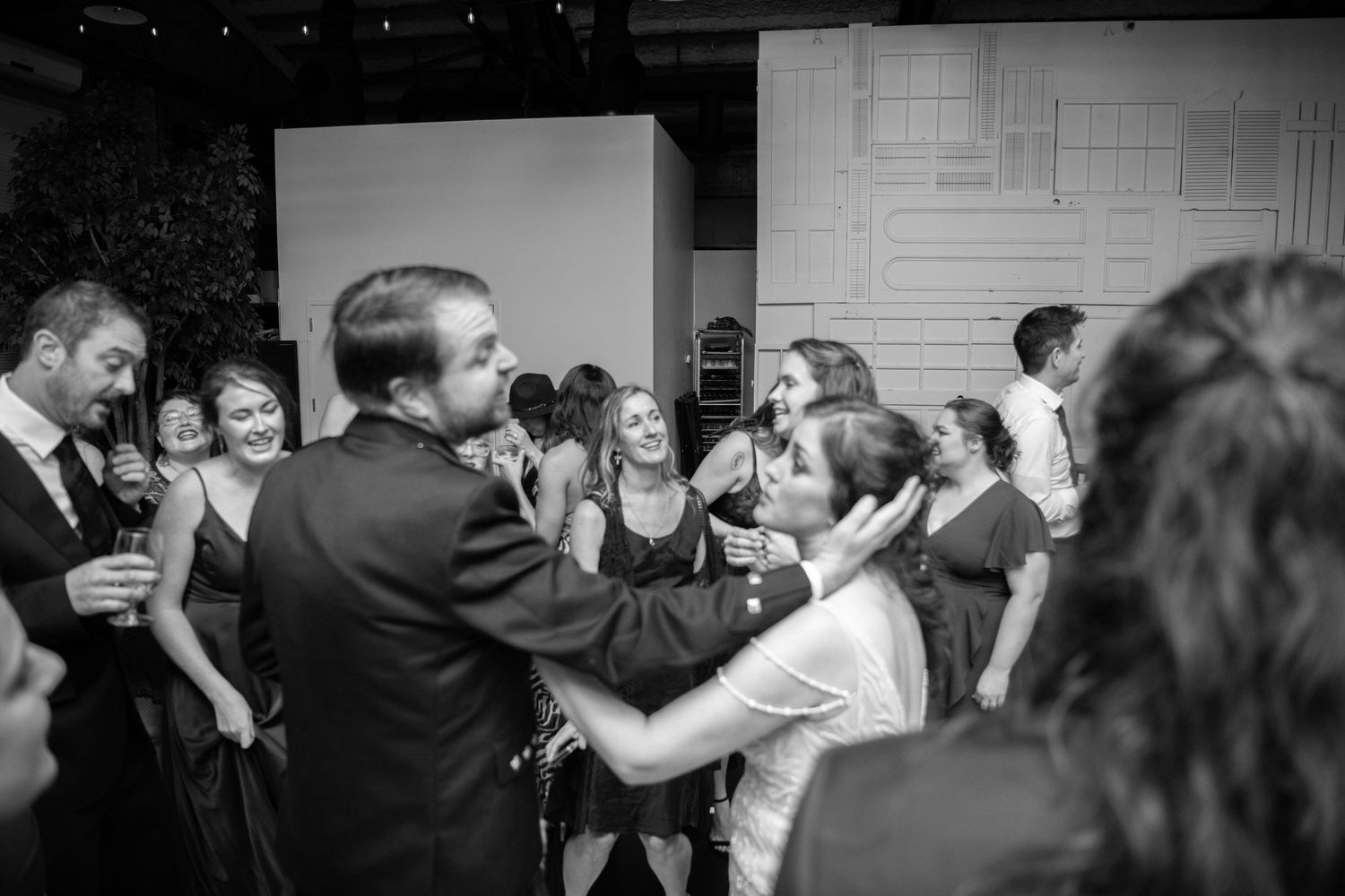 Black and white photo of wedding guests dancing and celebrating on the dance floor.
