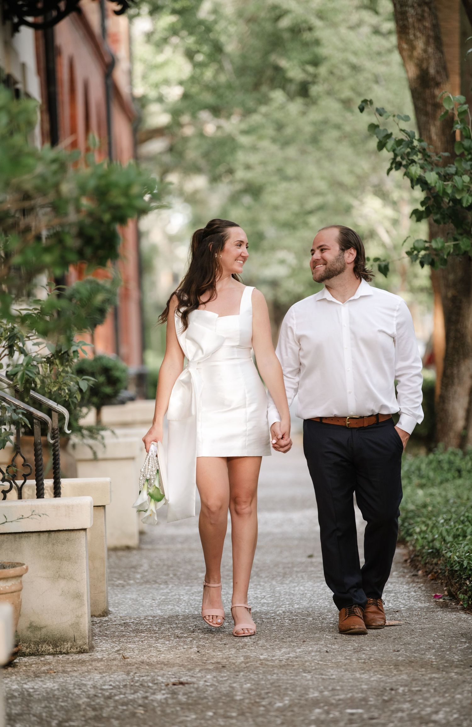 Couple walking away on cobblestone path holding hands in white and black attire, shown in sequence of romantic shots.