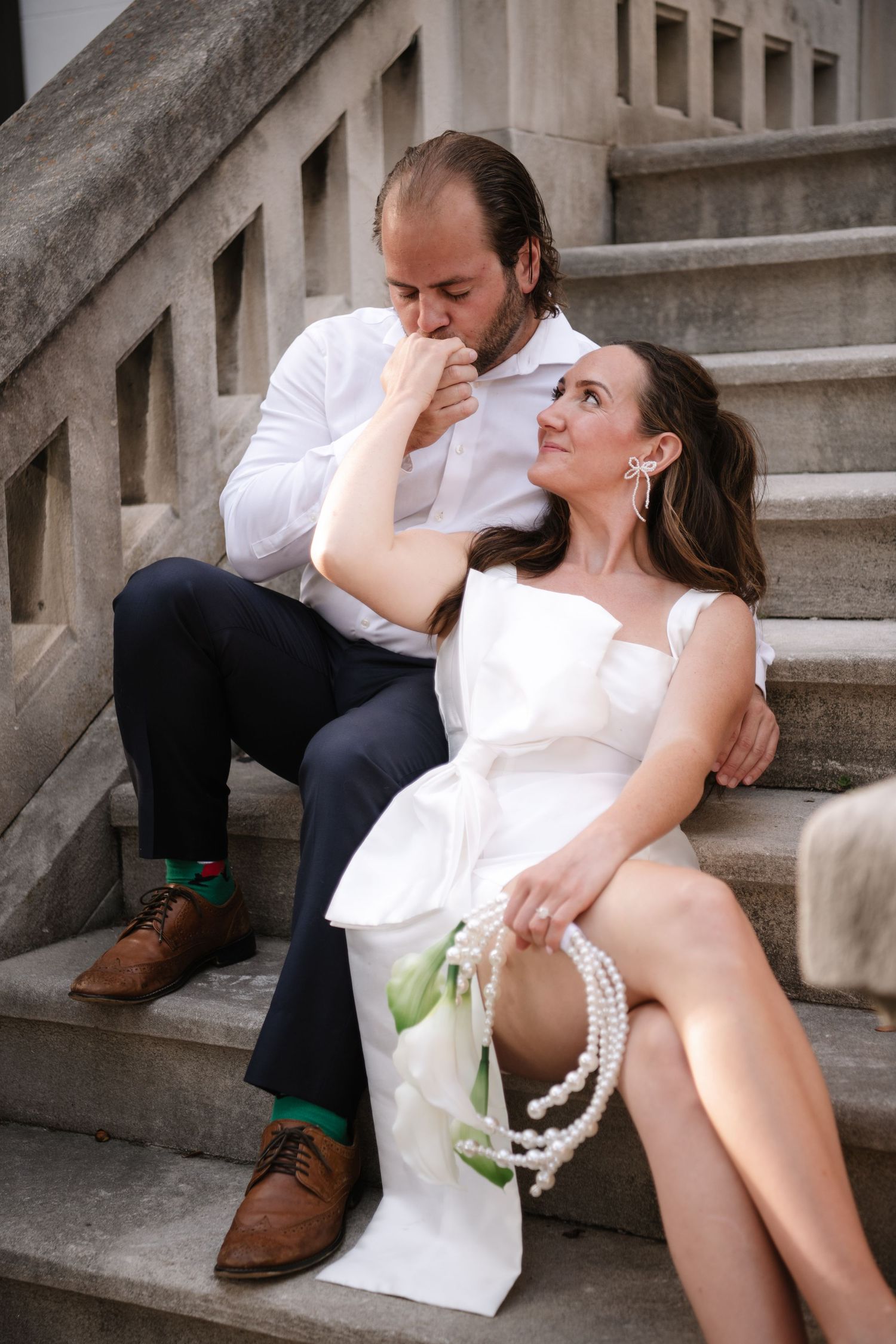 A romantic couple in white clothing poses intimately on stone steps in a series of artistic photographs.