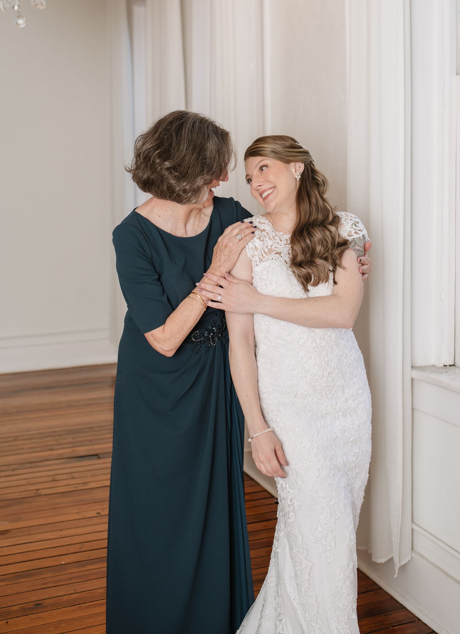 Tender moment captured in elegant room with white wedding dress and formal attire.