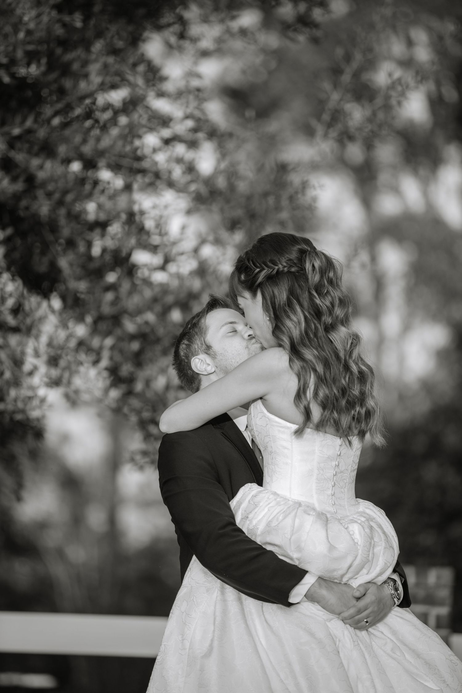 Black and white portrait of a romantic embrace between newlyweds outdoors.