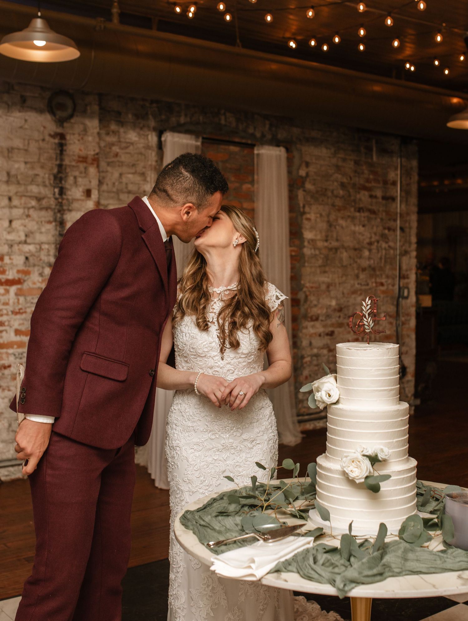 Couple cuts their elegant white tiered wedding cake at reception.