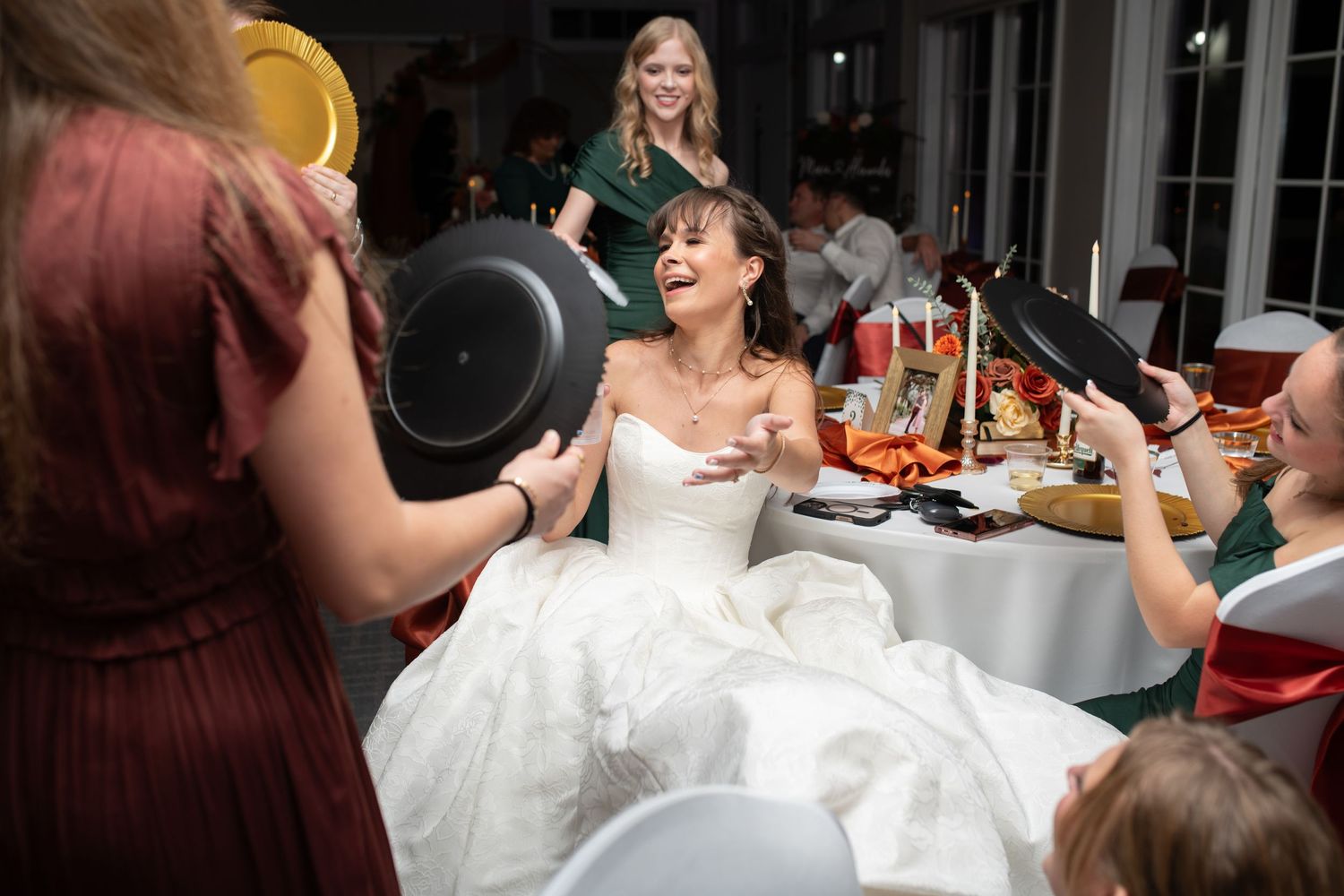 A bride in white surrounded by guests during the wedding reception dinner.