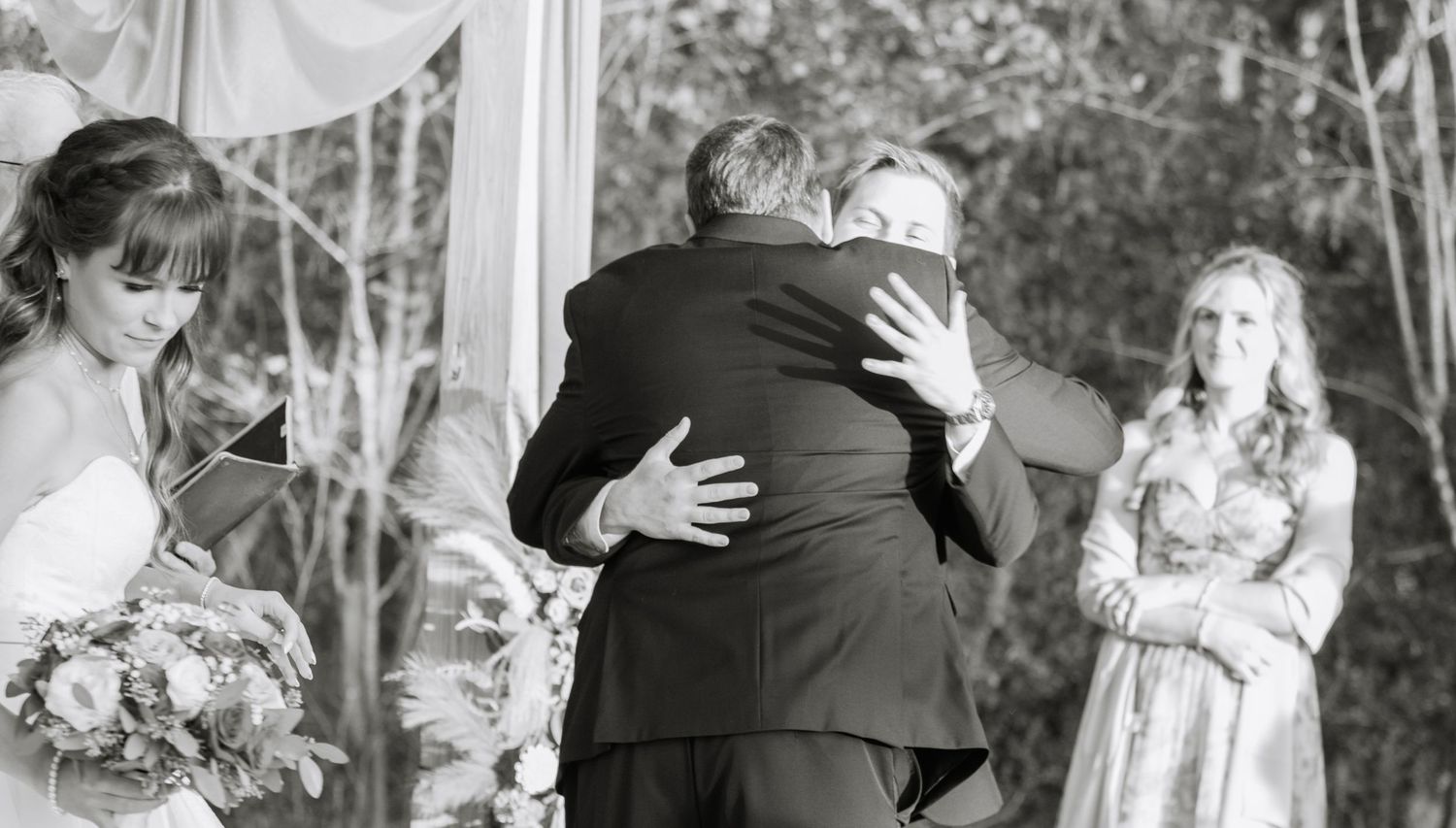 Wedding party shares emotional moments during outdoor ceremony.
