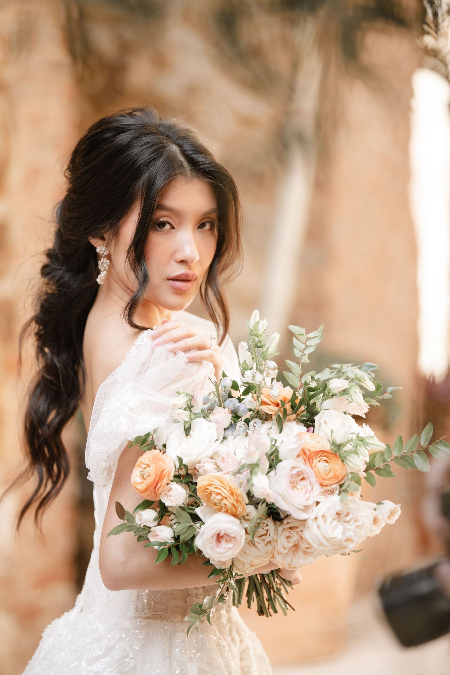 Beautiful bridal bouquet with peach roses and white flowers against a soft neutral background.