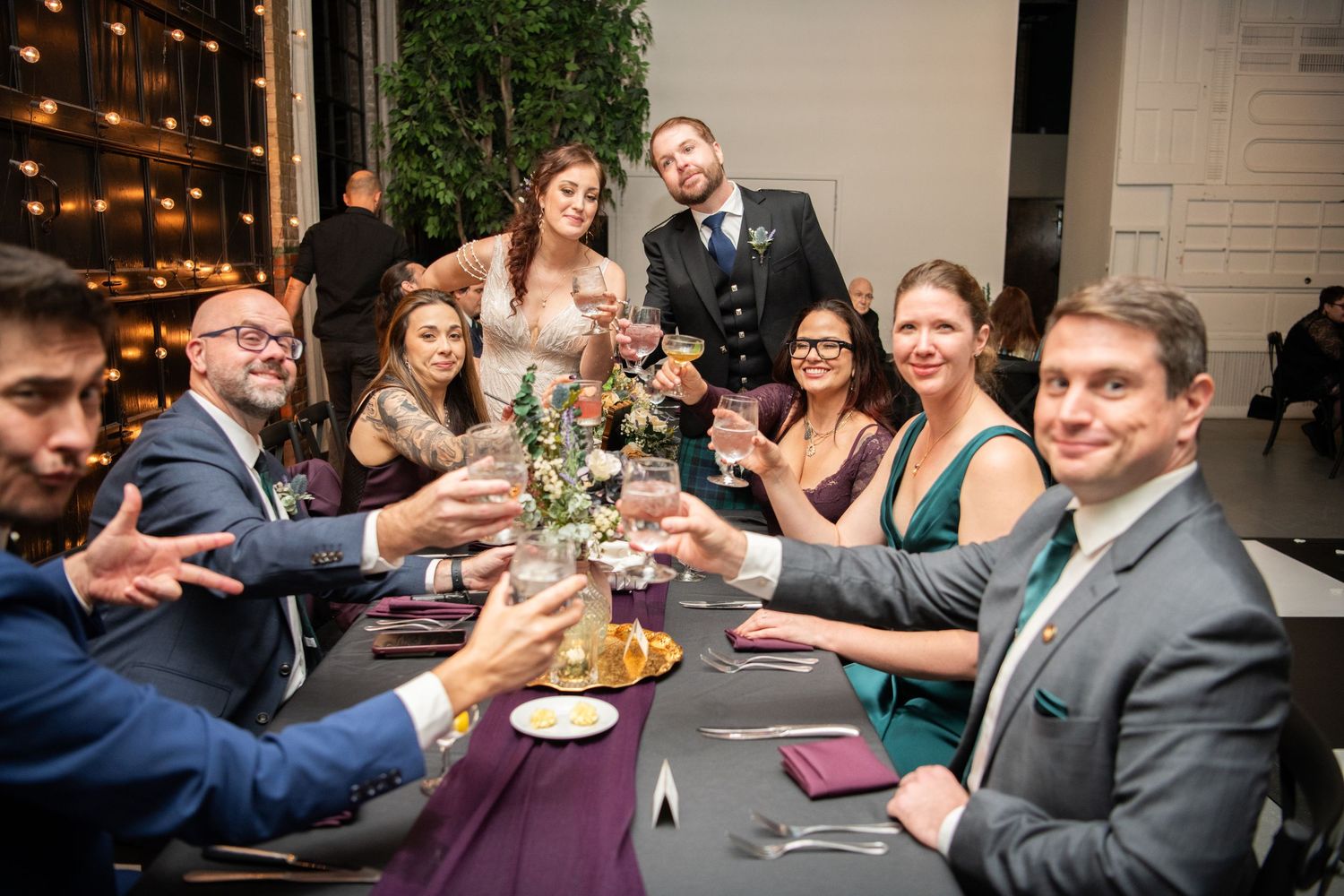 Wedding guests enjoying dinner and conversation at decorated tables with ambient lighting.