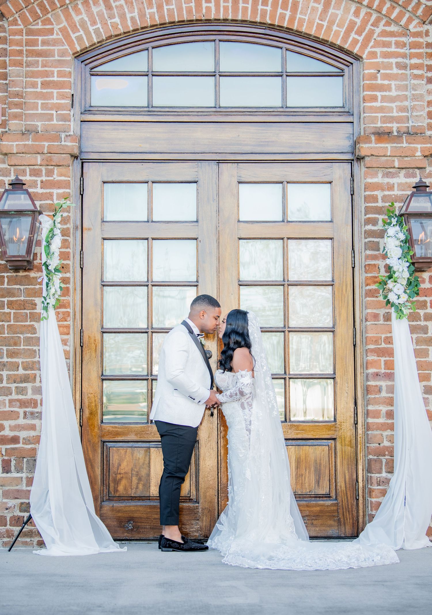 Wedding couple poses in various romantic stances against brick building with wooden doors.