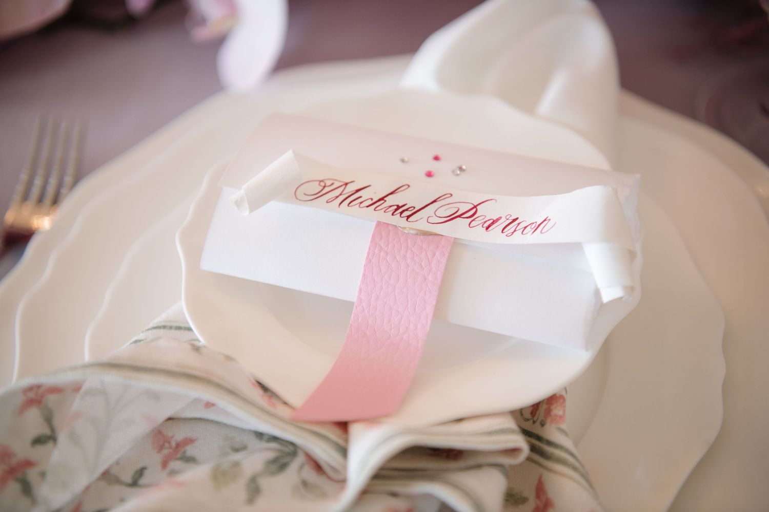 Close-up of formal white place settings with pink accents and name cards.
