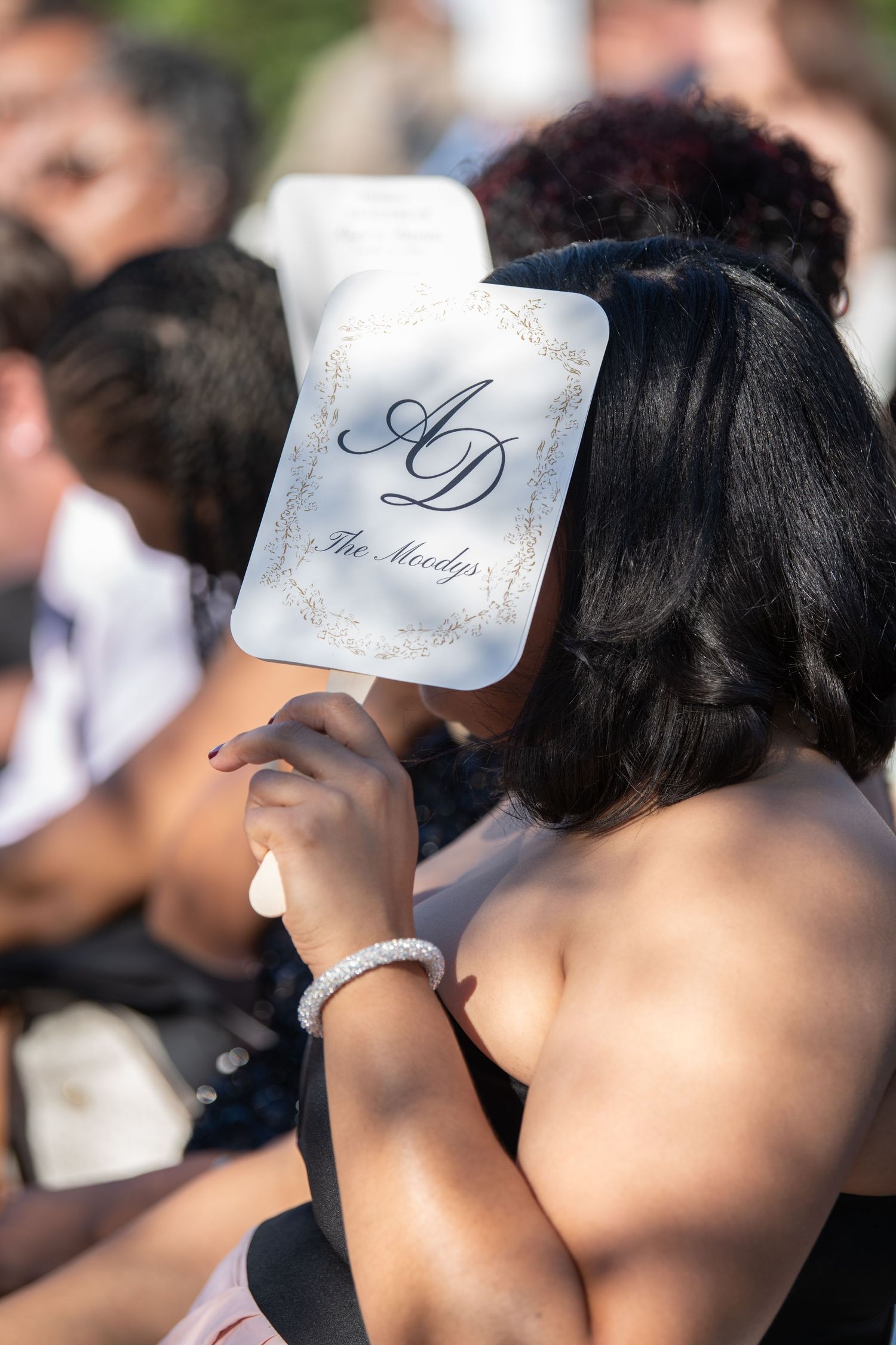 Wedding party members holding white name cards during outdoor ceremony.