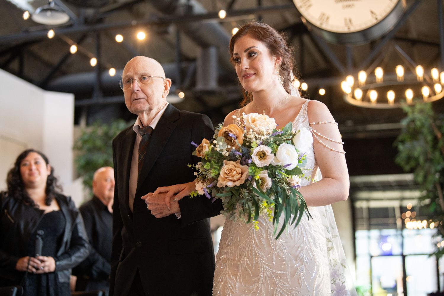 Wedding celebration in a rustic venue decorated with string lights and floral arrangements.